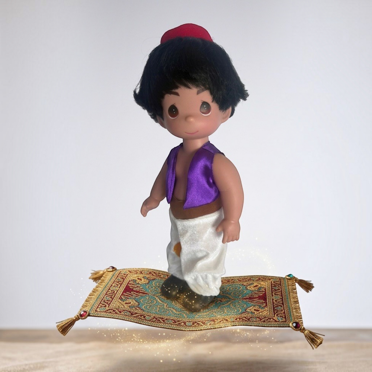 The Doll Maker 12-inch Aladdin doll wearing a purple vest and white pants standing on a miniature magic carpet