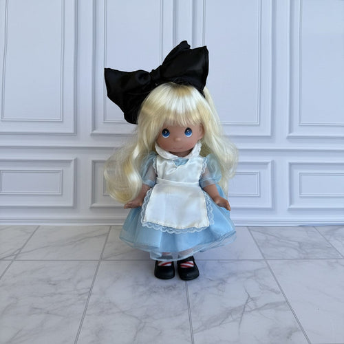 The Doll Maker 12-inch Alice in Wonderland doll with blonde hair, blue dress, white apron, and large black hair bow.