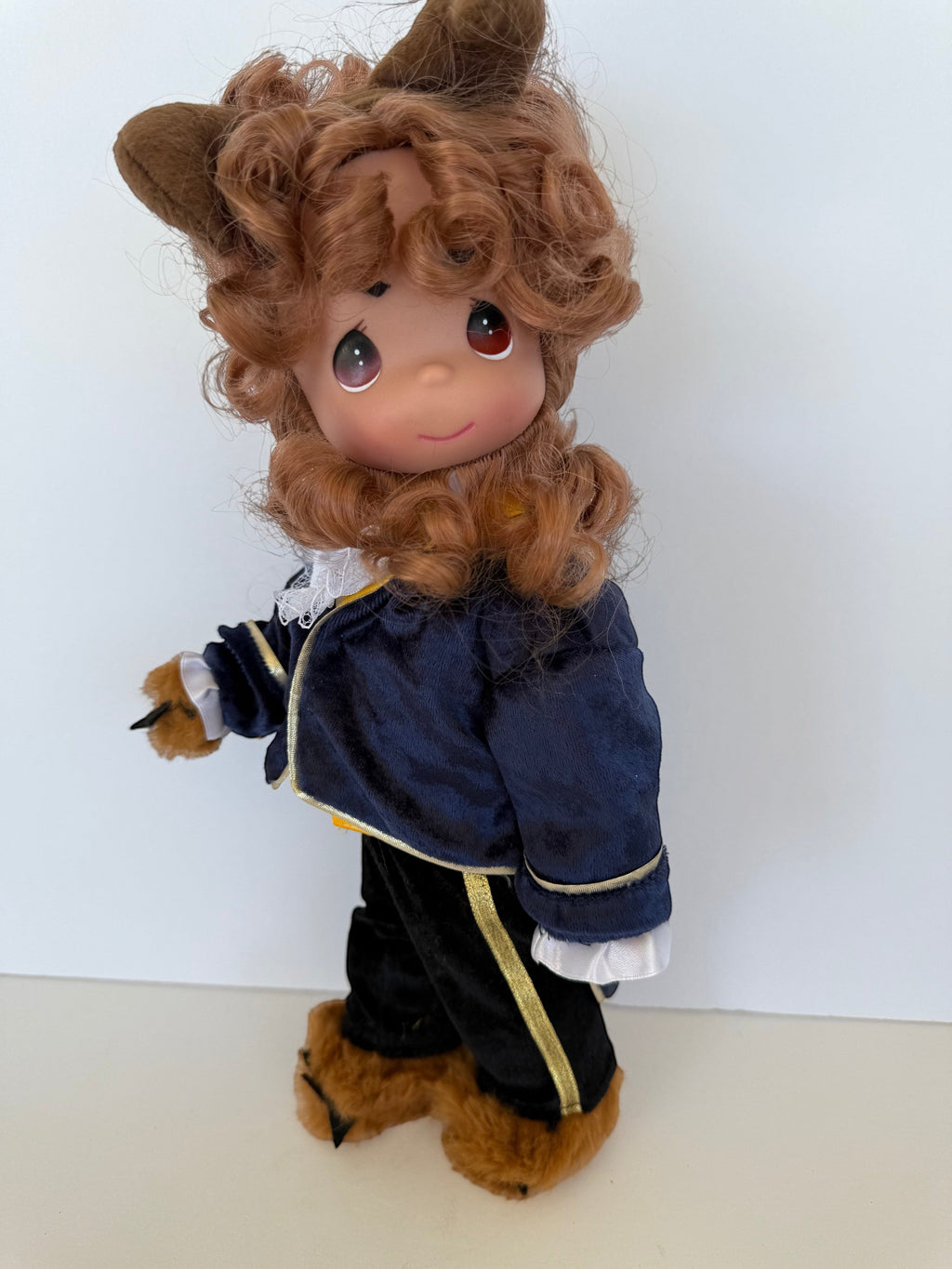 The Doll Maker 12-inch Beast doll with curly brown hair, wearing a navy blue velvet jacket and black trousers.