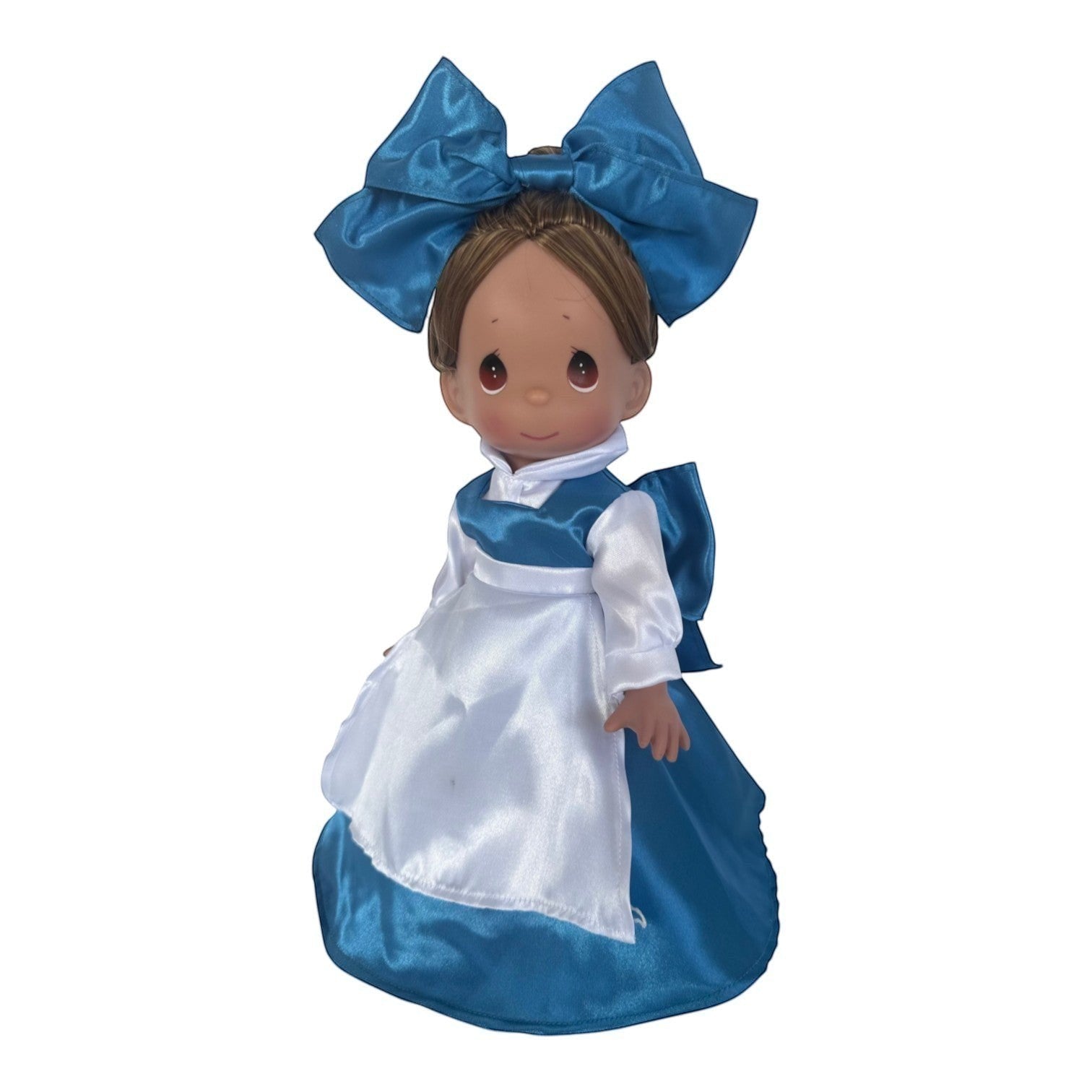 The Doll Maker 12-inch Belle doll wearing a blue dress with a white apron and a large matching blue hair bow.