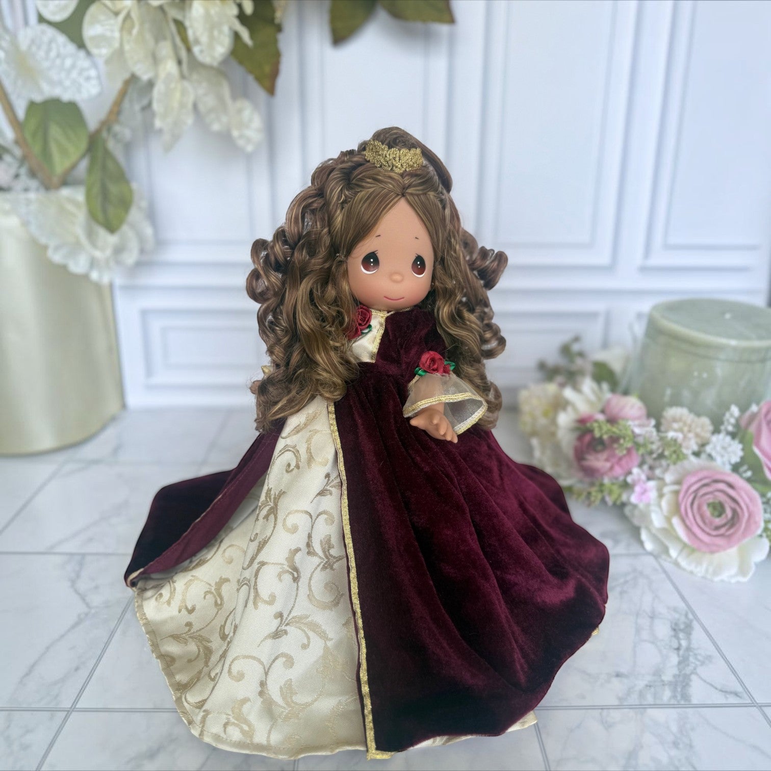 The Doll Maker 12-inch Belle Christmas doll wearing a burgundy velvet and gold brocade gown with a small gold crown.
