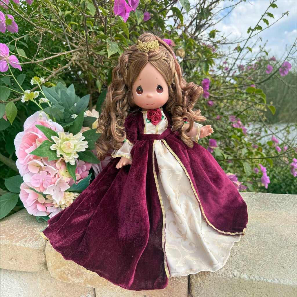 The Doll Maker 12-inch Belle Christmas doll wearing a burgundy velvet gown with gold accents and a small gold crown.