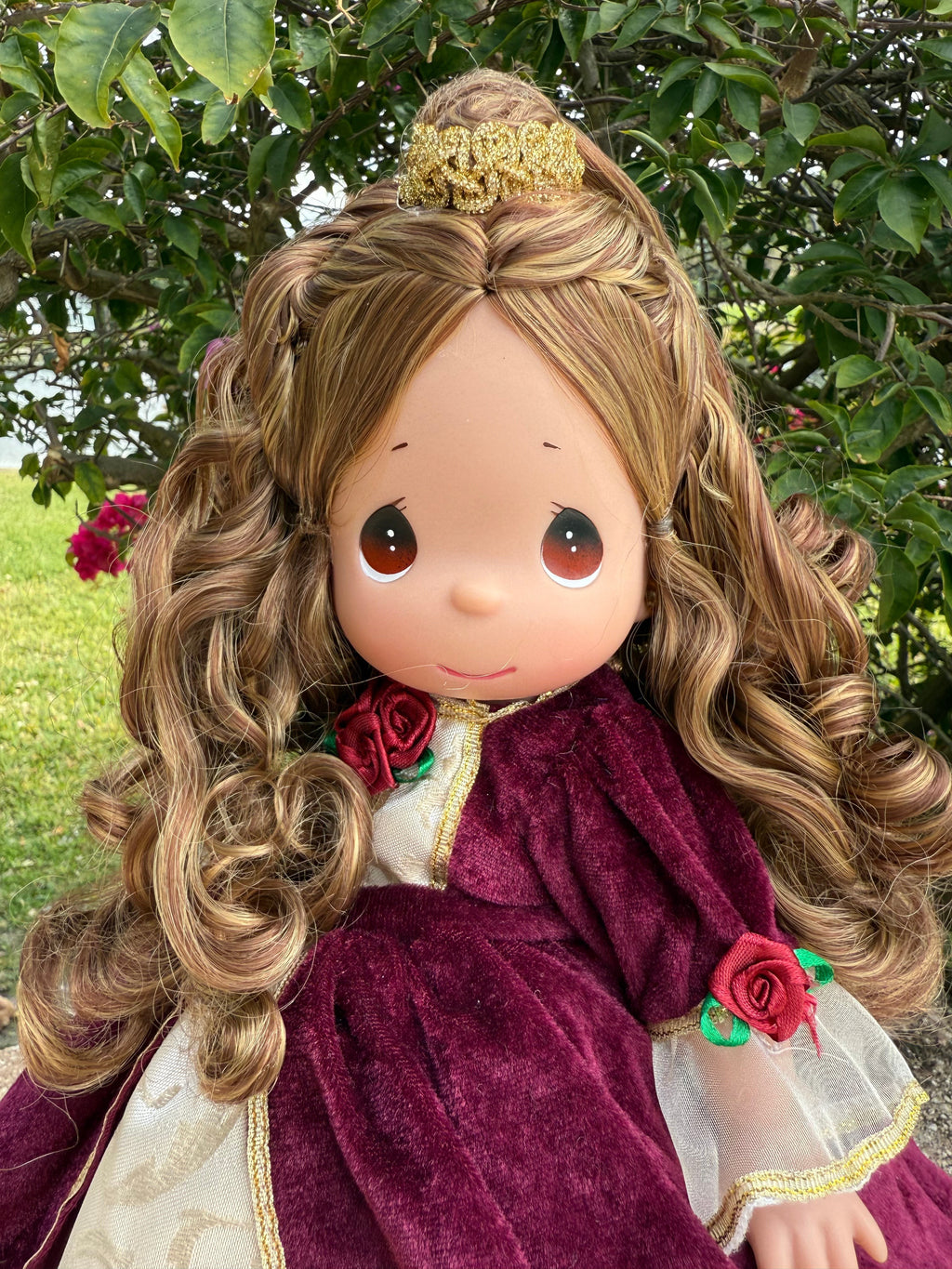 The Doll Maker Belle Christmas doll wearing a burgundy velvet dress with gold trim and red rose accents.