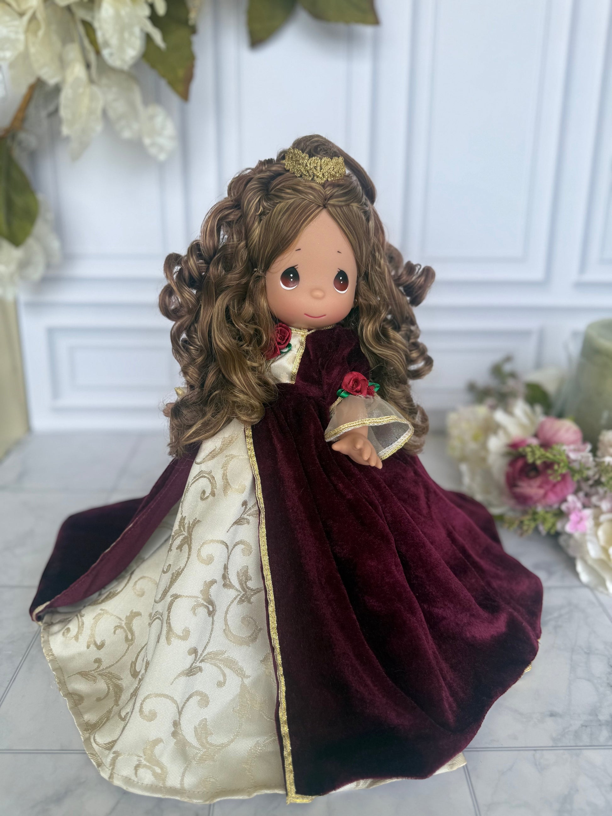 The Doll Maker 12-inch Belle Christmas doll wearing a burgundy velvet dress with gold floral accents