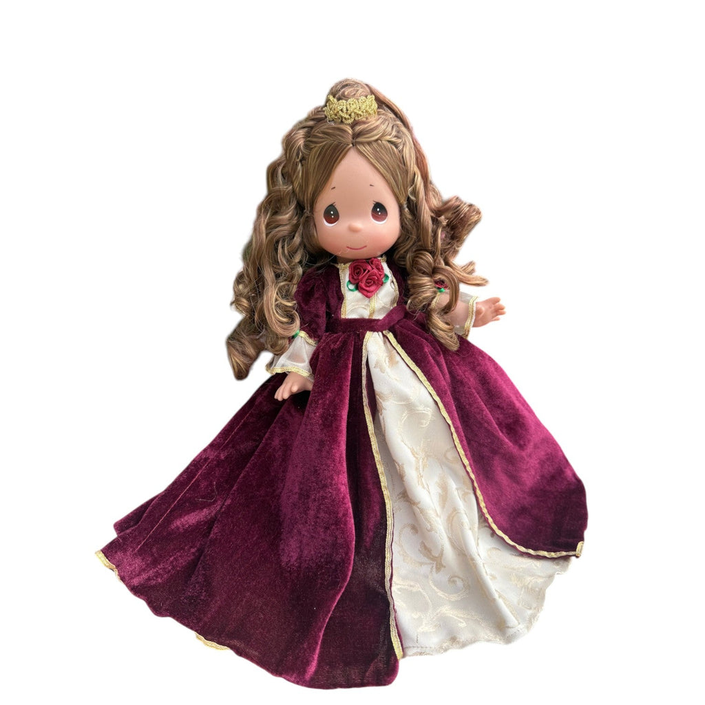 The Doll Maker 12-inch Belle doll wearing a burgundy velvet Christmas dress with gold trim and a small gold crown.