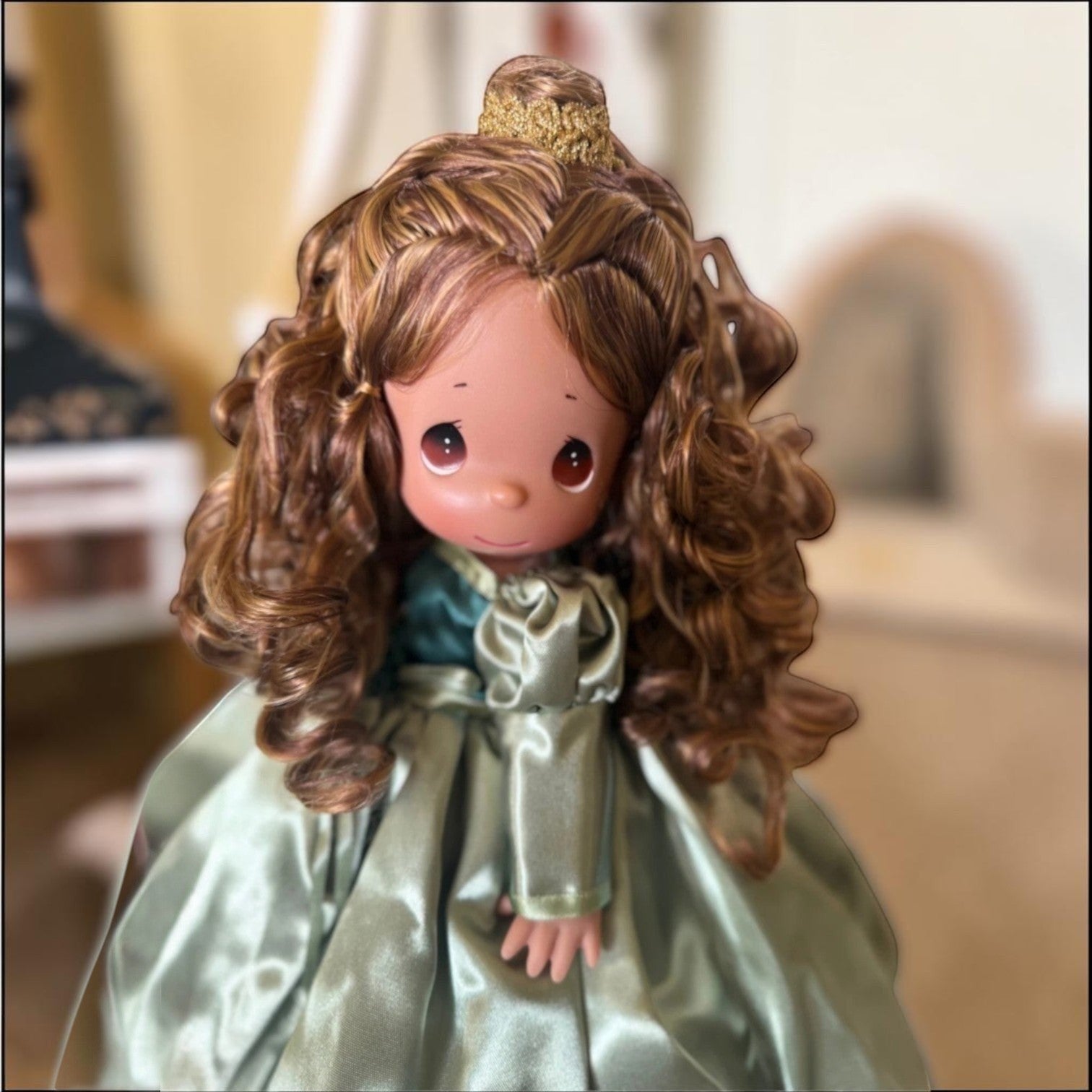The Doll Maker 12-inch Belle doll with curly brown hair, tear drop eyes, and a shimmering sage green satin gown.