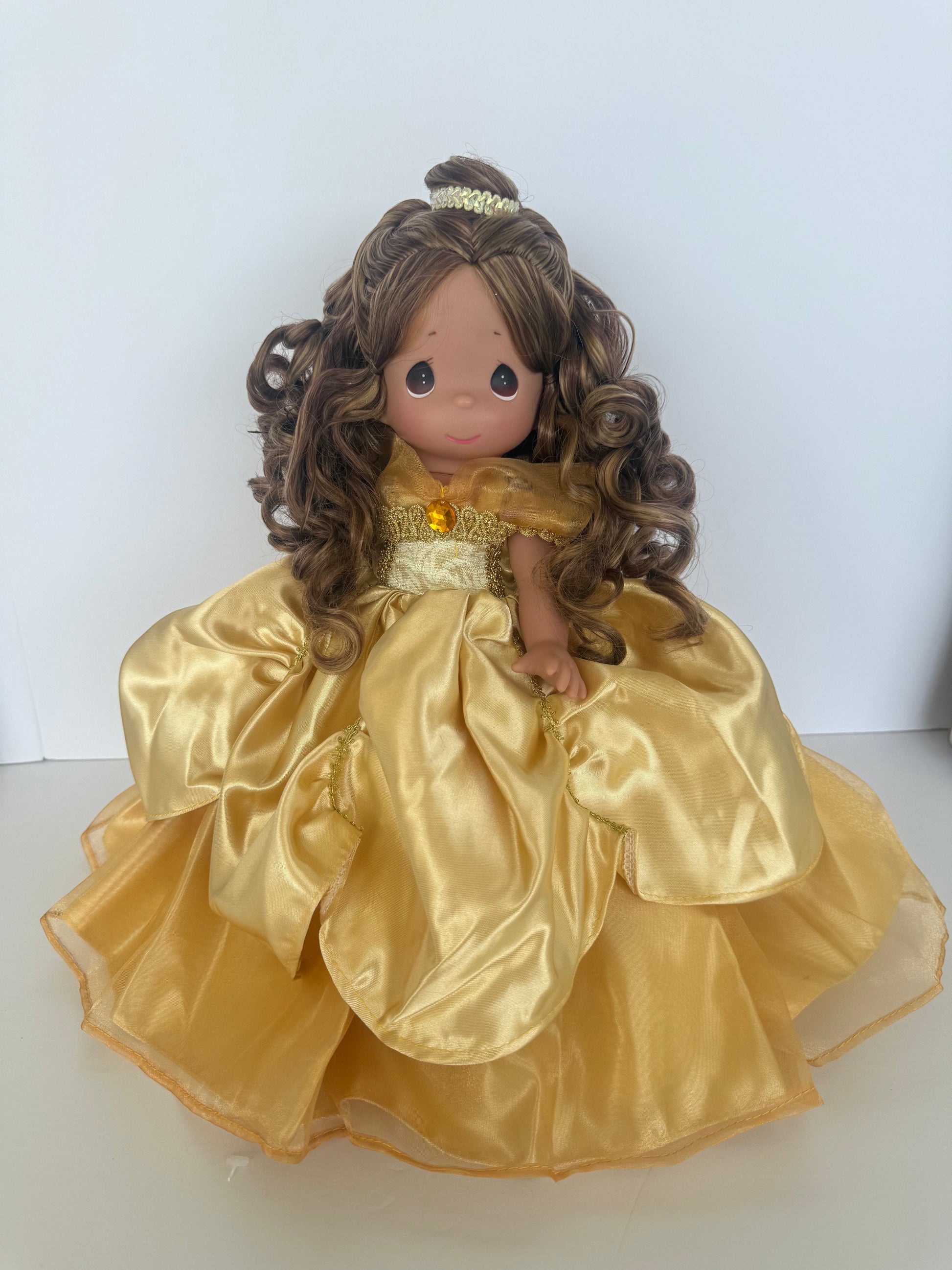 The Doll Maker 12-inch Belle doll with curly brown hair wearing an elegant gold satin ball gown