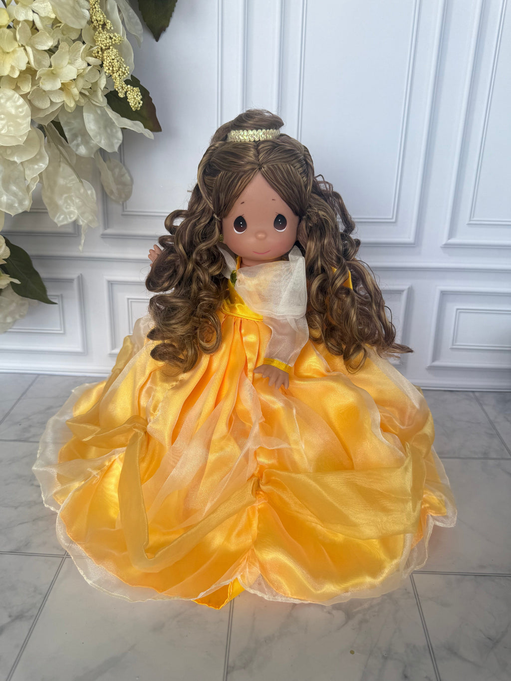The Doll Maker 12-inch Belle doll with long curly brown hair wearing a voluminous yellow organza ball gown