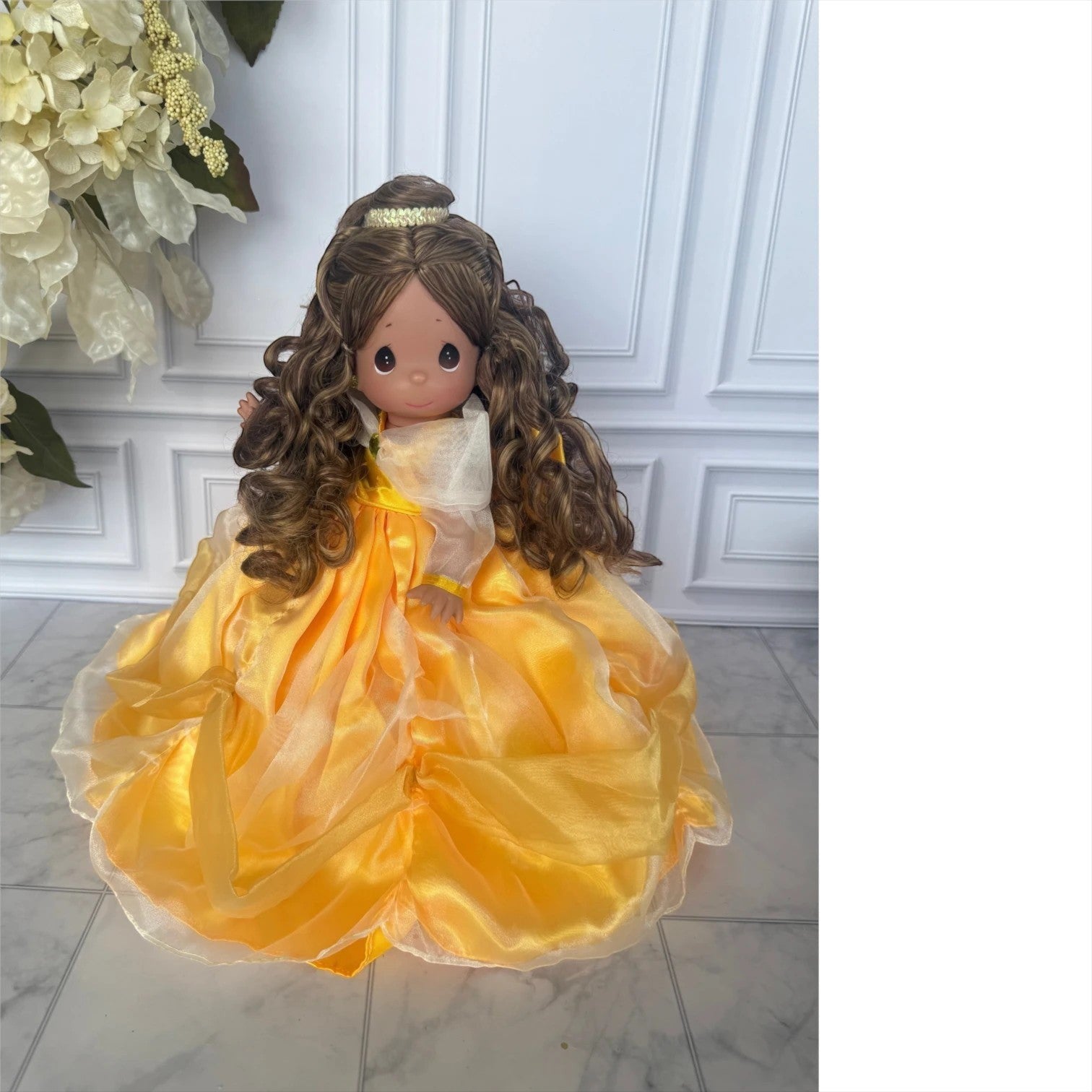 The Doll Maker 12-inch Belle doll with long curly brown hair wearing a voluminous yellow organza ball gown