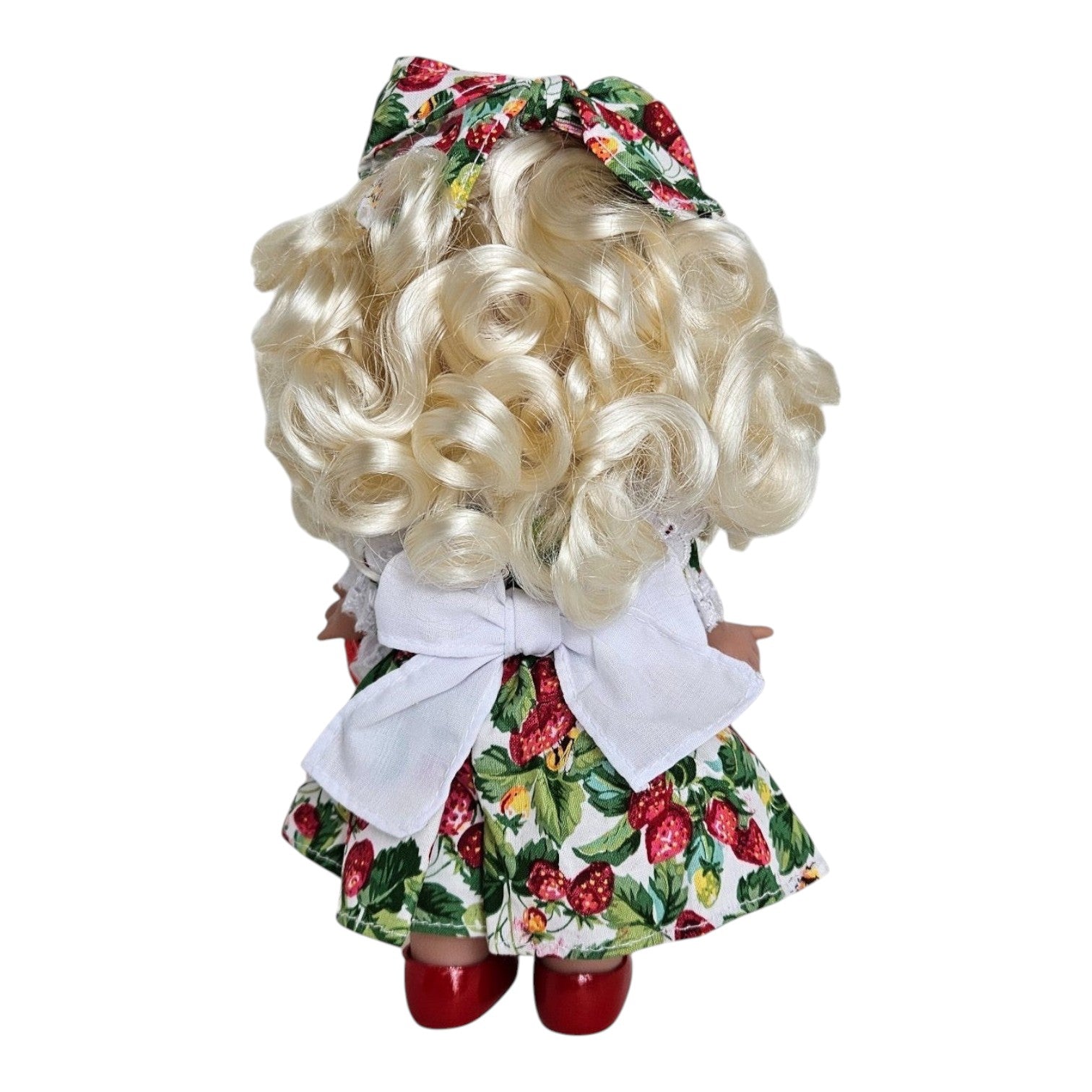 Back view of The Doll Maker You’re Berry Sweet 9-inch vinyl doll with blonde curls and strawberry print dress