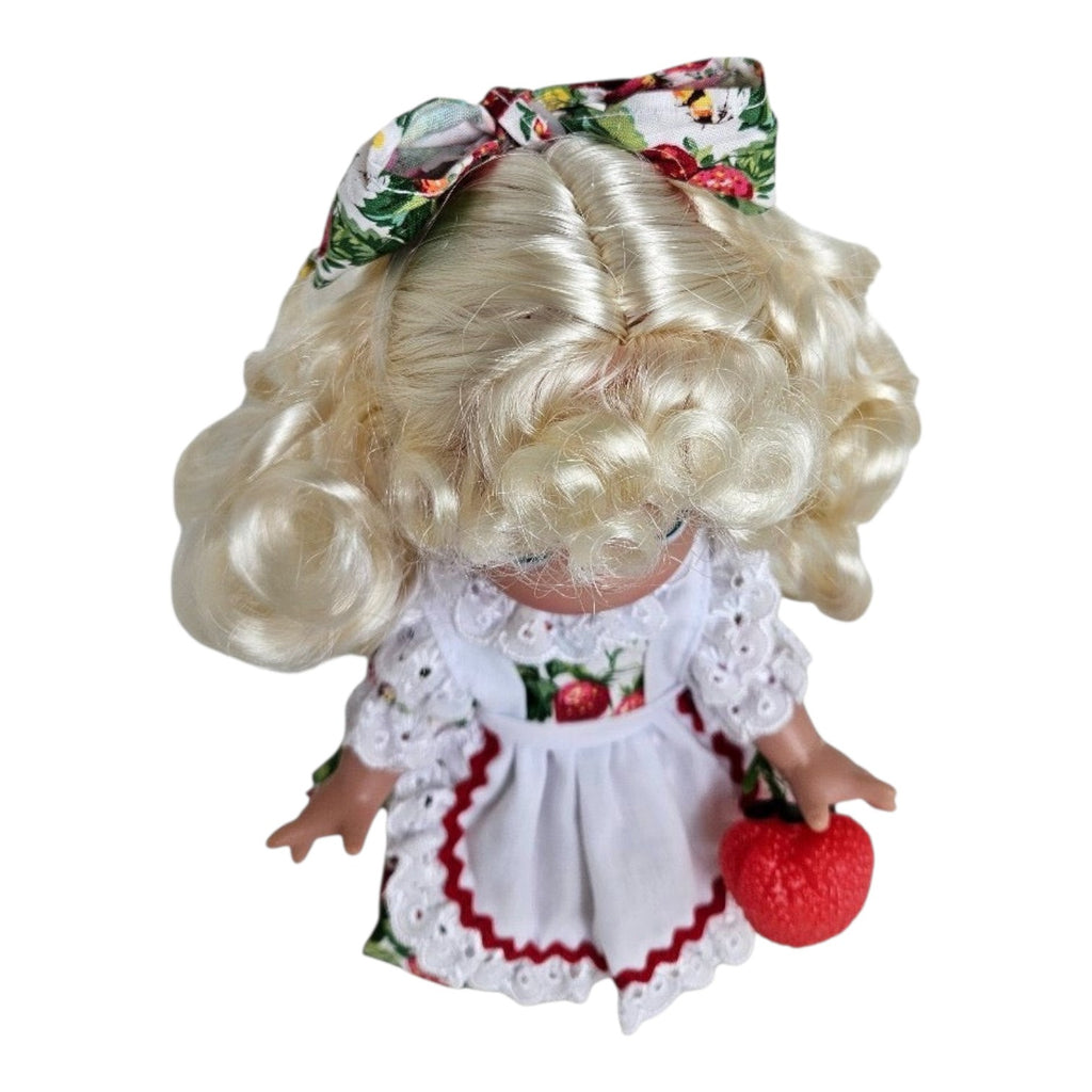 The Doll Maker You’re Berry Sweet 9-inch vinyl doll with blonde curls, strawberry print dress, and matching hair bow.