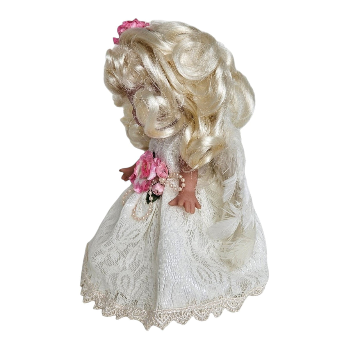 The Doll Maker 7-inch blonde angel doll wearing a white lace dress with pink floral accents and pearl details.