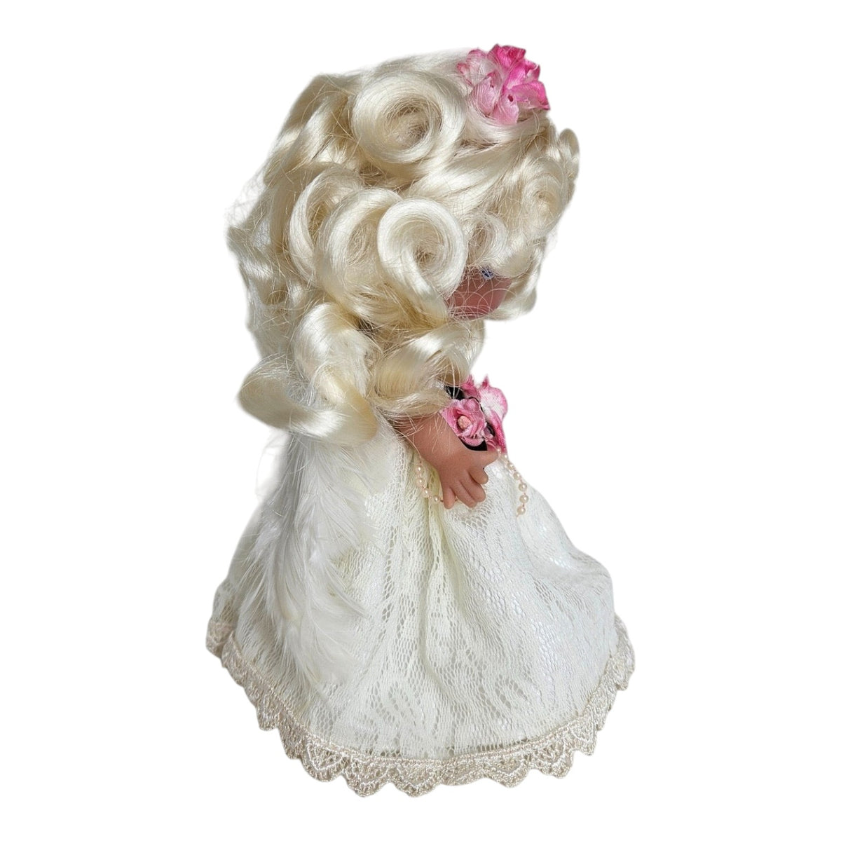 The Doll Maker 7-inch blonde angel doll wearing a white lace dress with pink floral accents, side profile view.