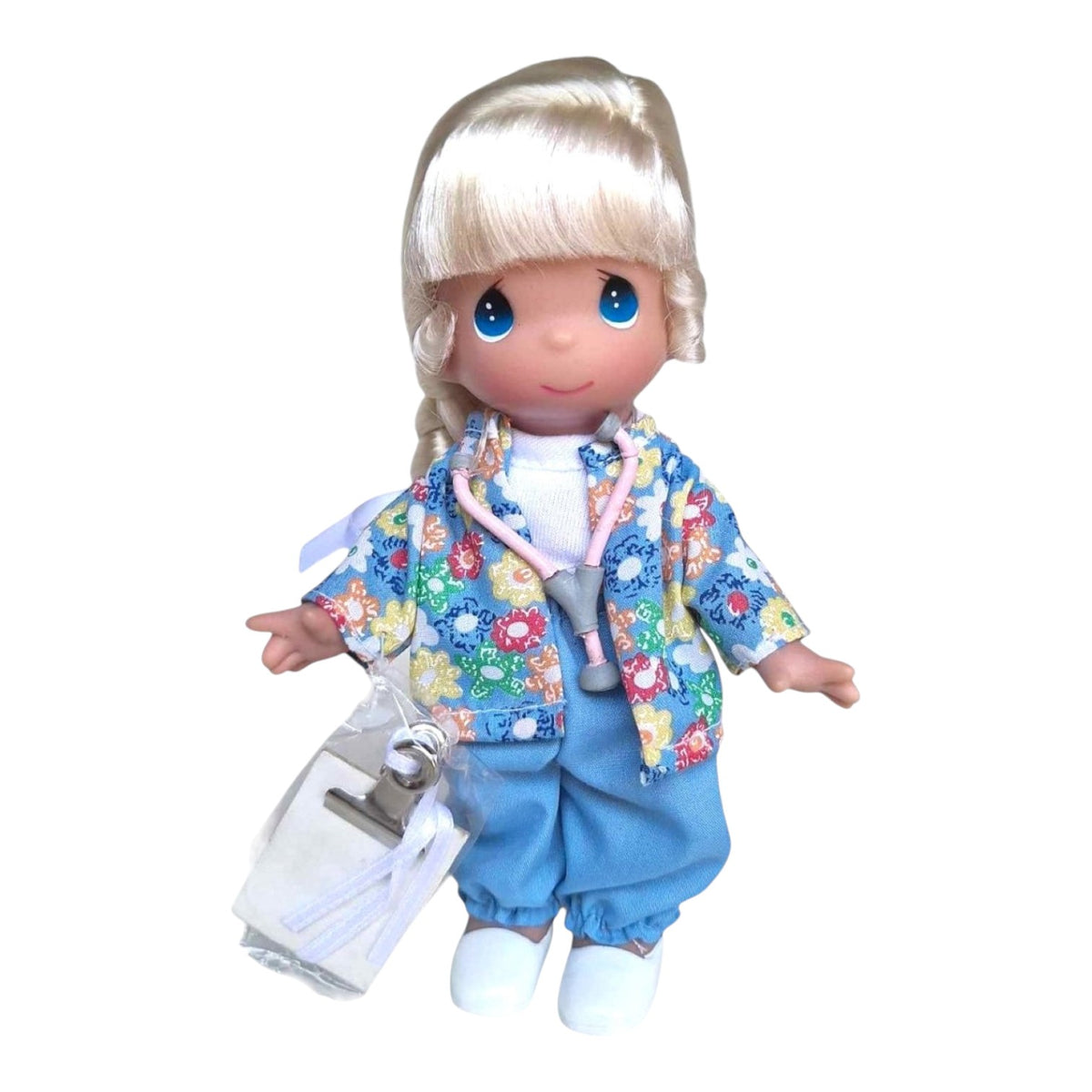 The Doll Maker Caring for You blonde nurse doll wearing a floral scrub top, blue pants, and a pink stethoscope.