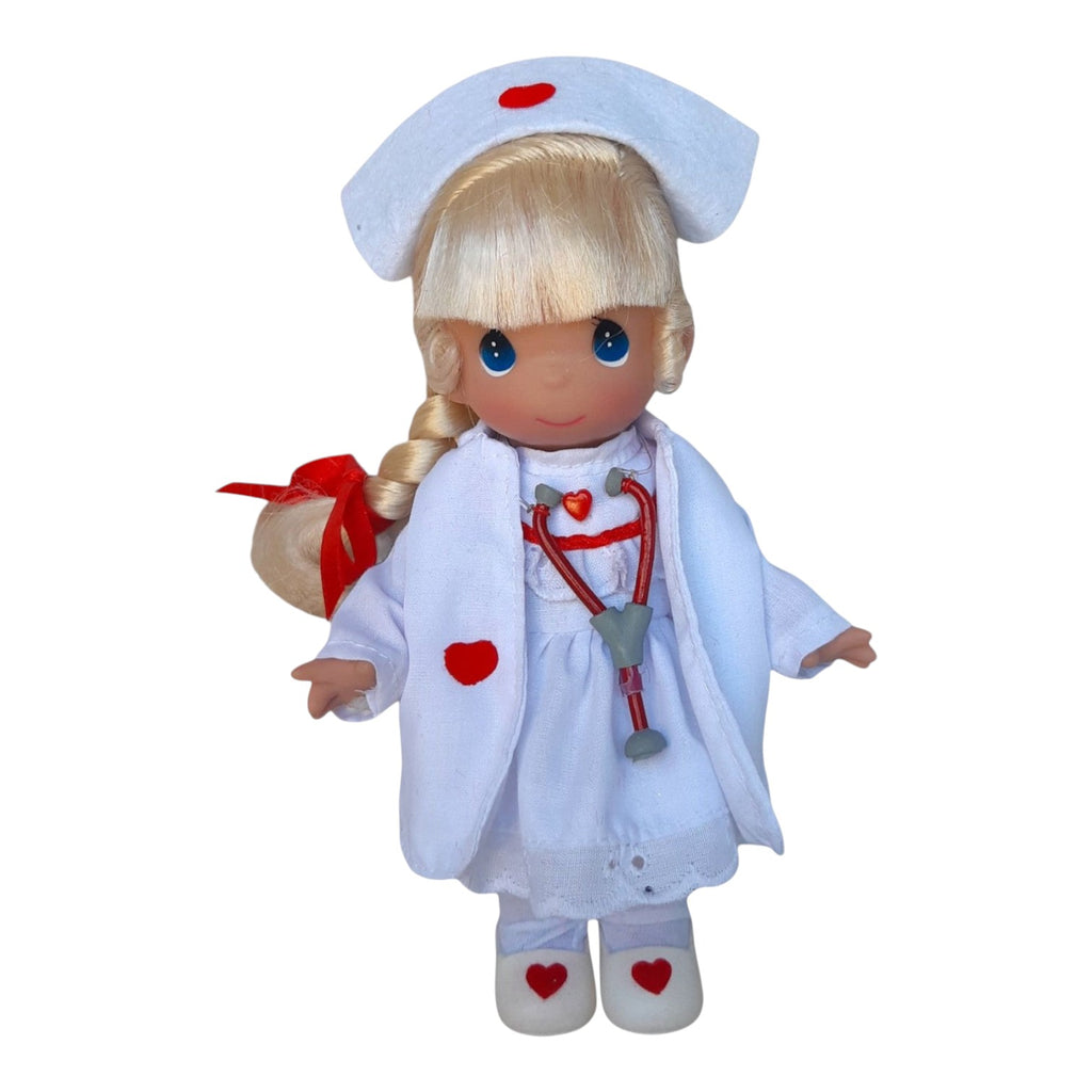 The Doll Maker Loving Touch blonde nurse doll wearing a white uniform with red heart accents and a stethoscope.