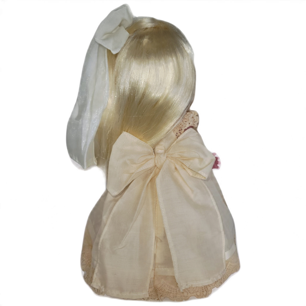 The Doll Maker Cherish Me Always blonde vinyl doll wearing an ivory lace gown with a large back bow, rear view