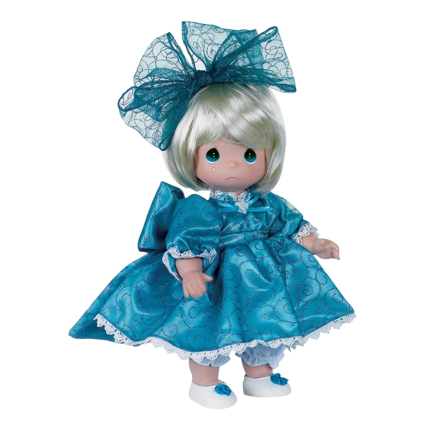 The Doll Maker 12-inch blonde vinyl doll wearing a teal dress with glittery swirls and a matching oversized hair bow.