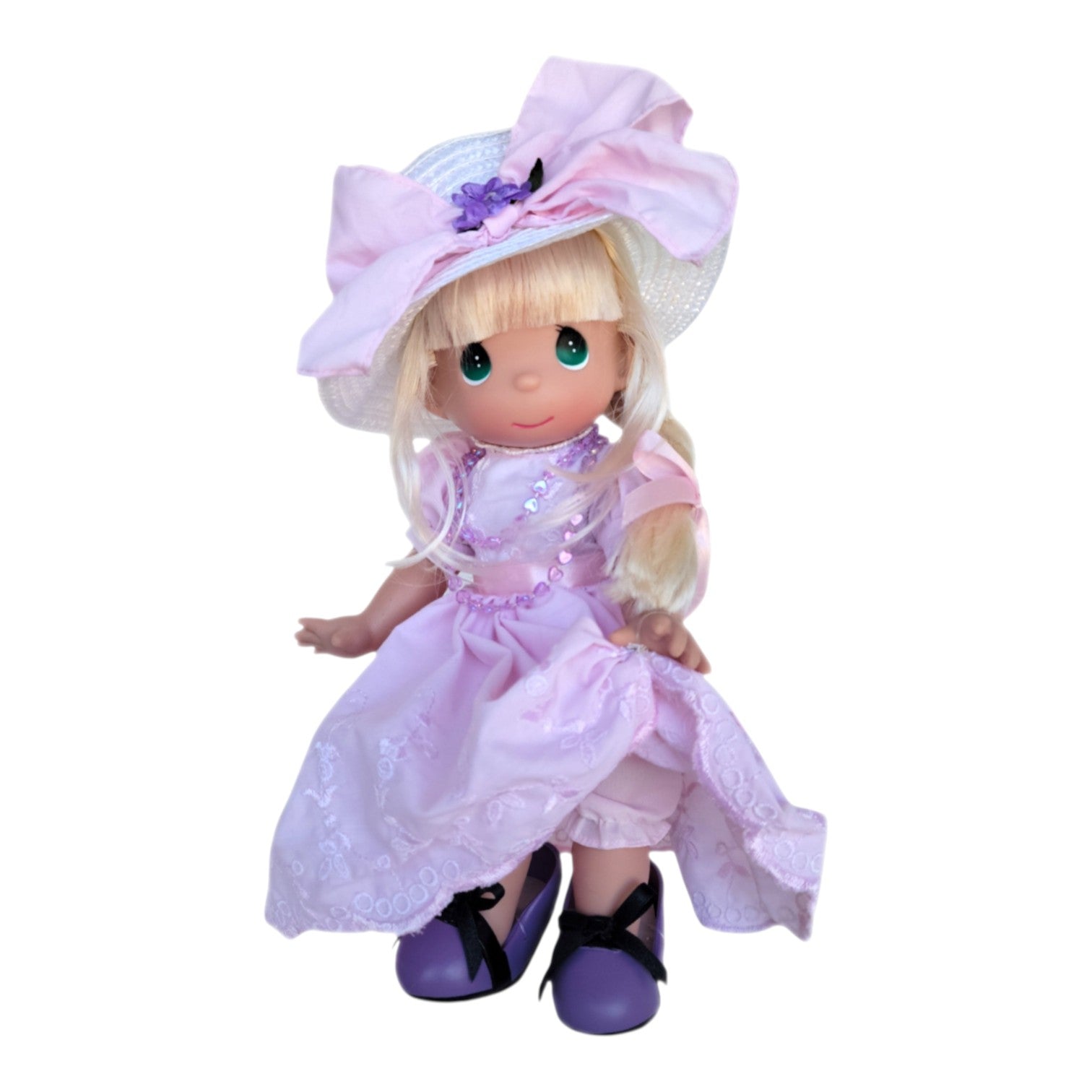 The Doll Maker 12-inch blonde Precious Moments doll wearing a pink dress, pink necklace, and over sized purple shoes.