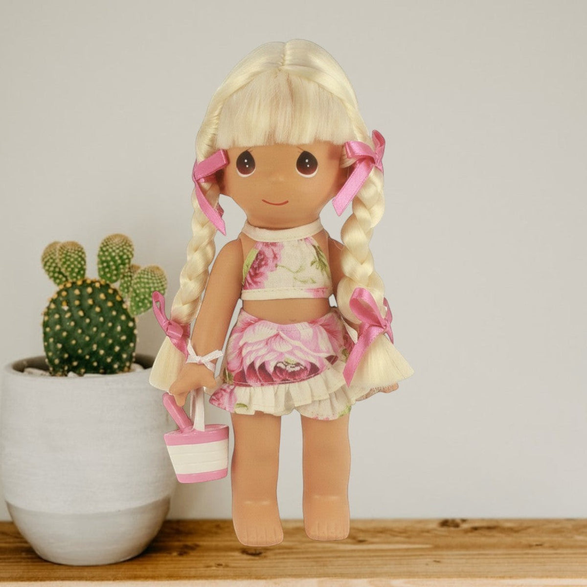 The Doll Maker Sand Castle Dreams 9-inch blonde vinyl doll with braided hair, wearing a floral two-piece beach outfit.