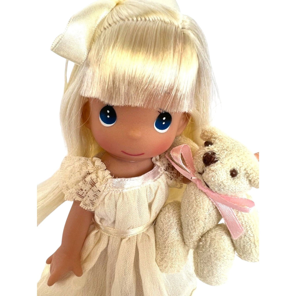 The Doll Maker 7-inch blonde vinyl doll wearing an ivory lace gown and holding a small teddy bear with a pink ribbon.