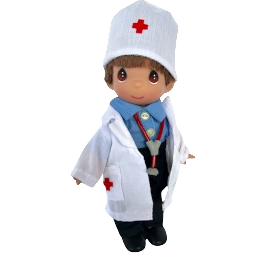 The Doll Maker 7-inch boy doctor doll wearing a white lab coat, blue shirt, and medical cap with red cross details.