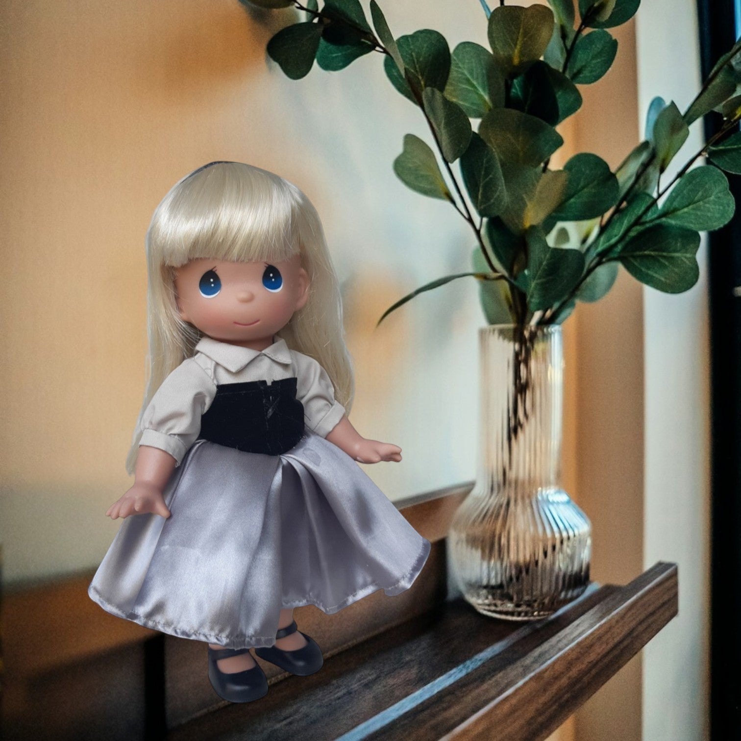 The Doll Maker 12-inch Briar Rose peasant doll with blonde hair, gray skirt, and black bodice on a wooden shelf.