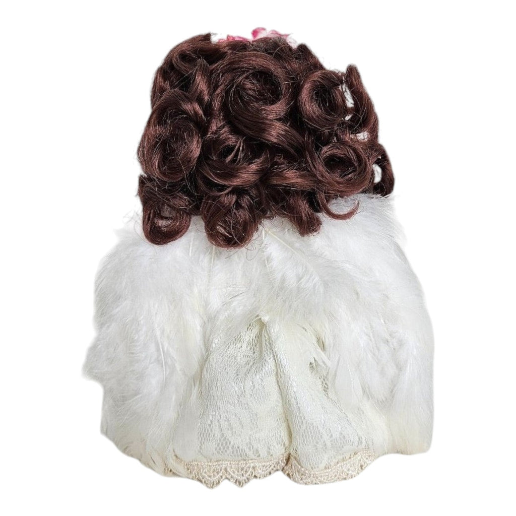 The Doll Maker 7-inch brunette angel doll featuring curly brown hair and a white feathered lace dress, back view.