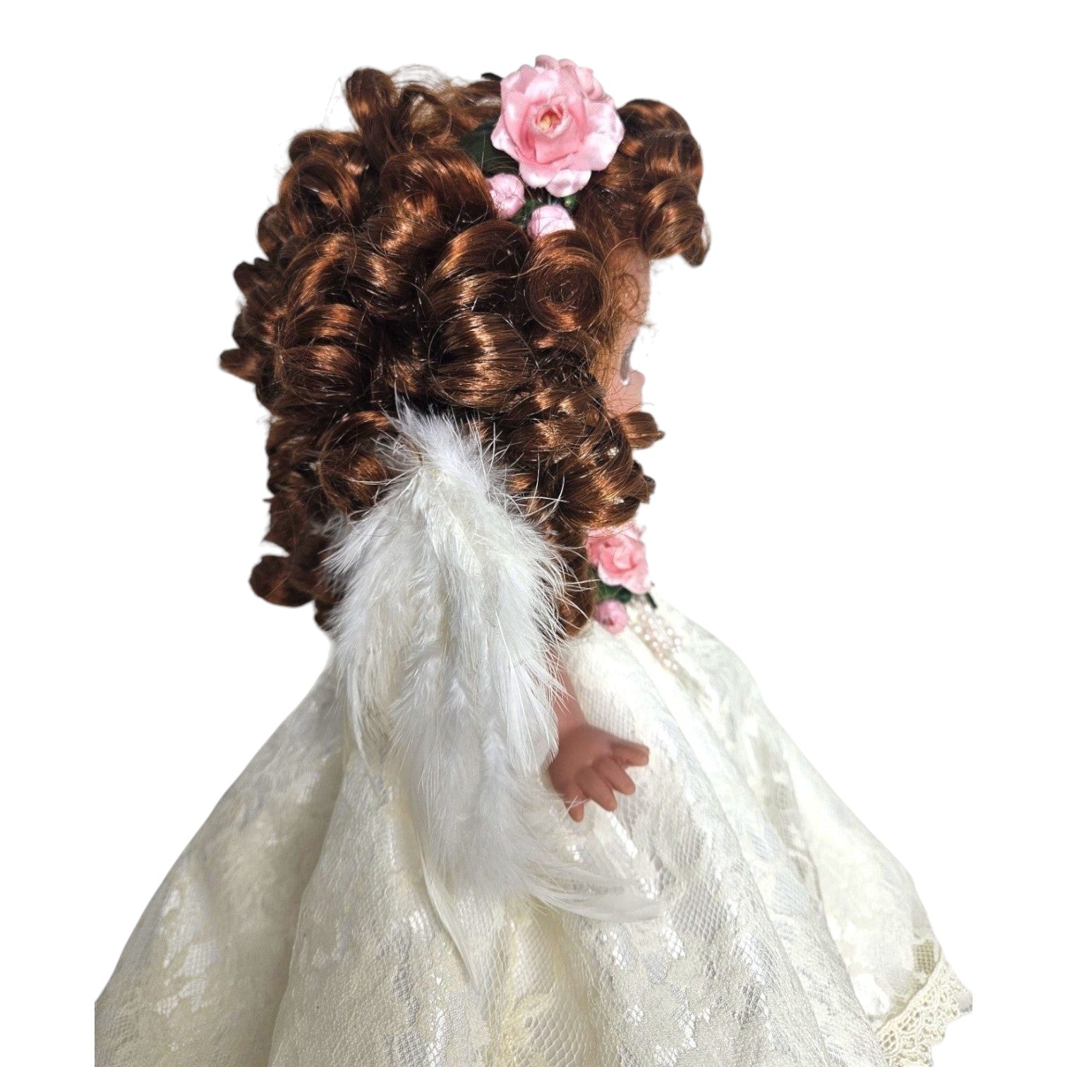The Doll Maker 12-inch brunette angel doll wearing a white lace dress with feathered wings and pink floral hair decor.