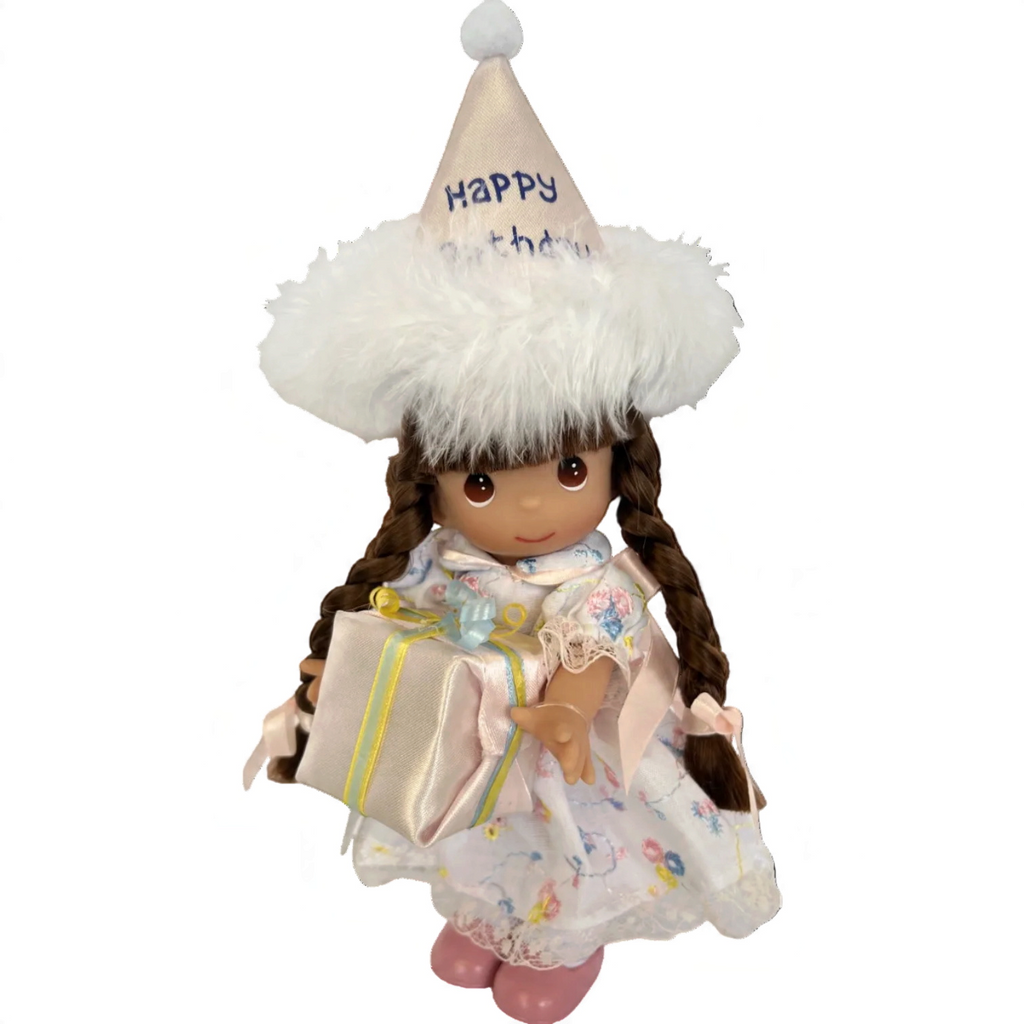 The Doll Maker 7-inch brunette vinyl birthday doll wearing a party hat and holding a gift box.