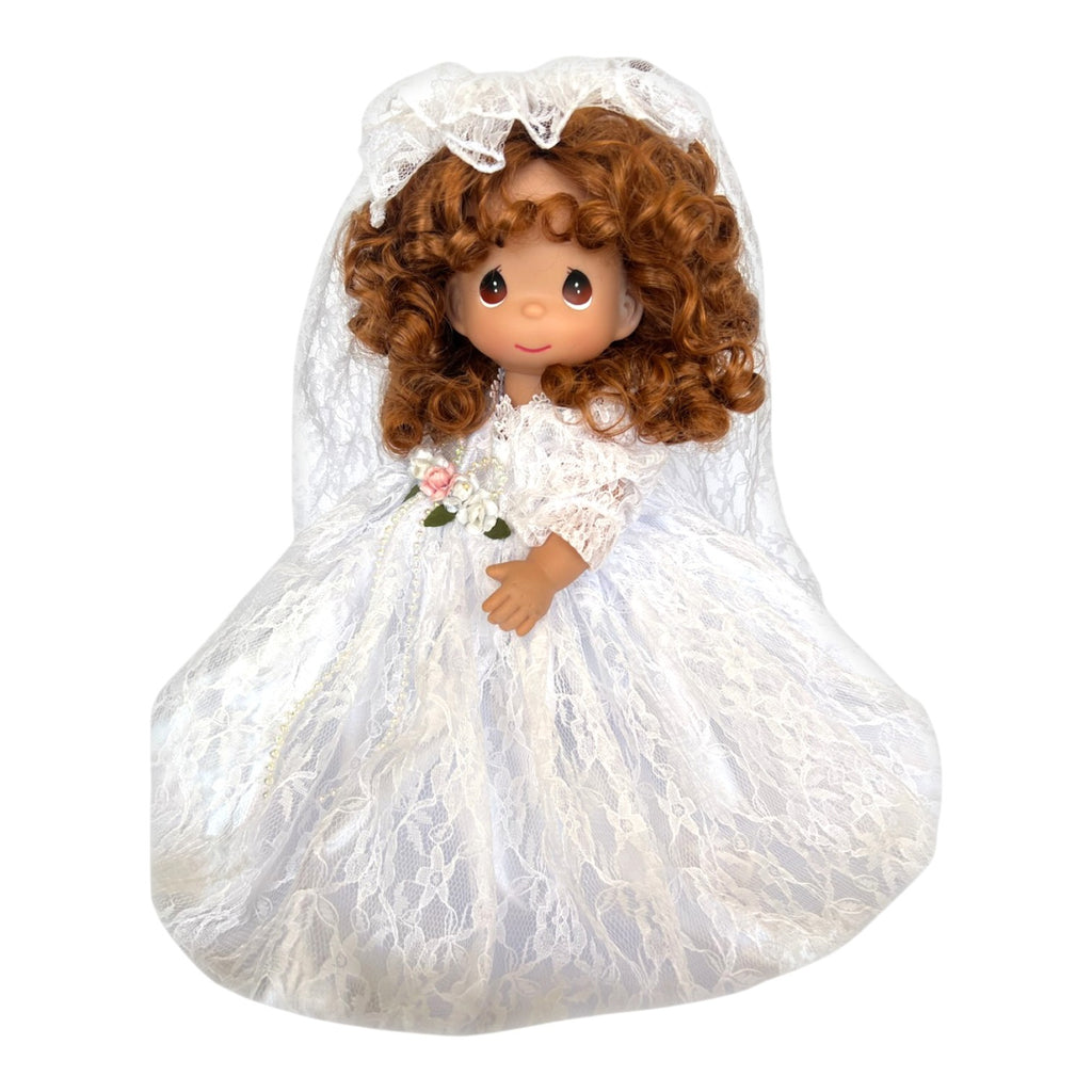 The Doll Maker 12-inch brunette bride doll wearing a white lace wedding dress and veil with floral accents.