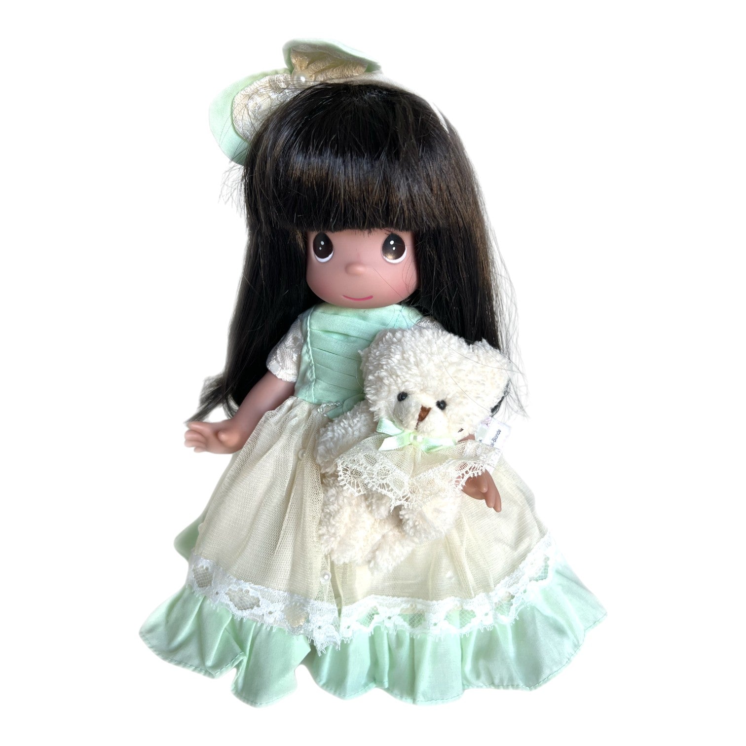The Doll Maker Bear-y Special 12-inch brunette doll wearing a green and ivory dress, holding a small white teddy bear.