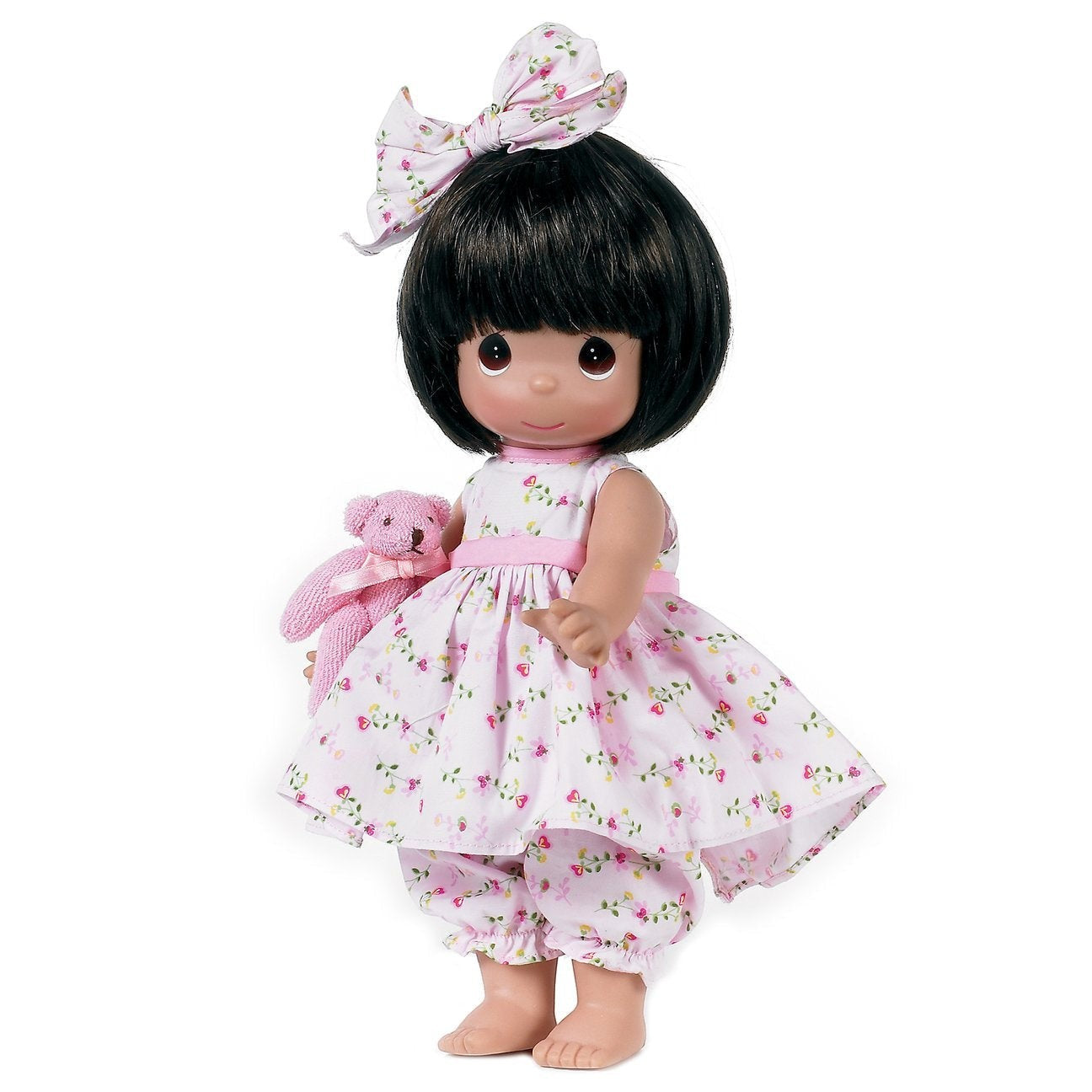 The Doll Maker 12-inch brunette vinyl doll wearing a floral dress and matching hair bow, holding a small pink bear.