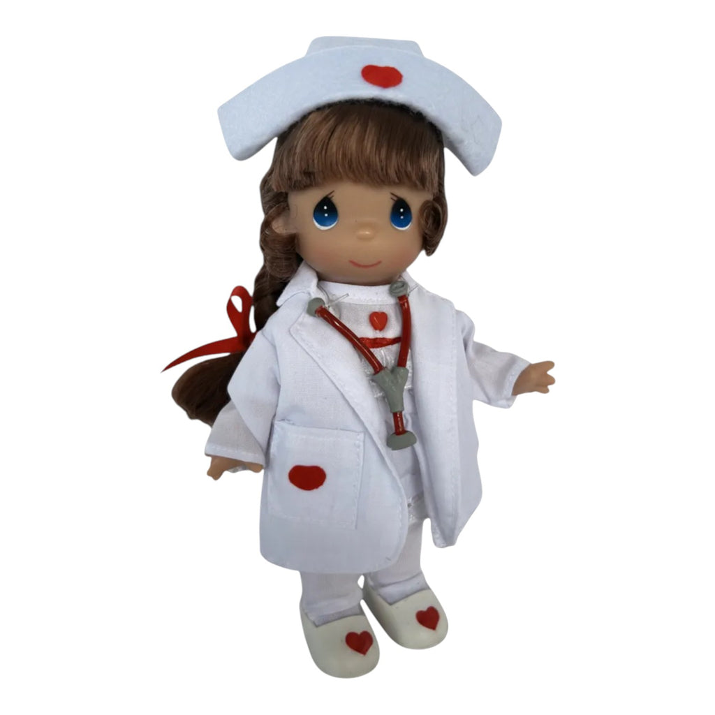 The Doll Maker 7-inch brunette nurse doll wearing a white uniform with red heart accents and a stethoscope