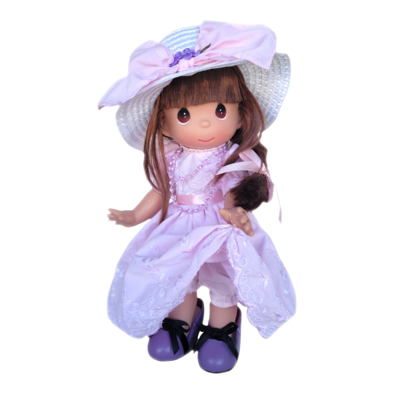 The Doll Maker 12-inch brunette Precious Moments doll wearing a pink dress, pink necklace, and oversized purple shoes.