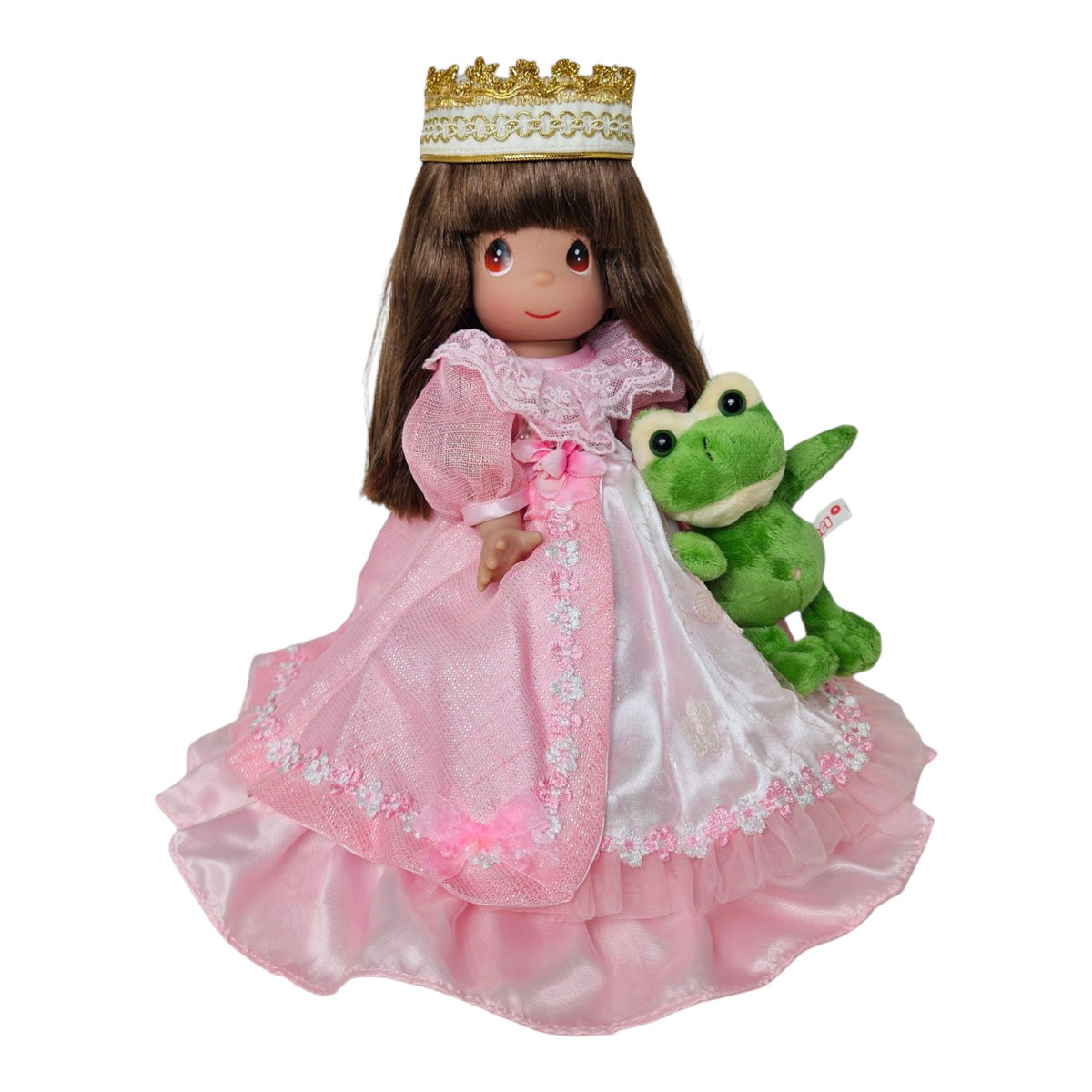 The Doll Maker 12-inch brunette doll wearing a pink princess dress, lace trim, and gold crown, holding a plush frog.