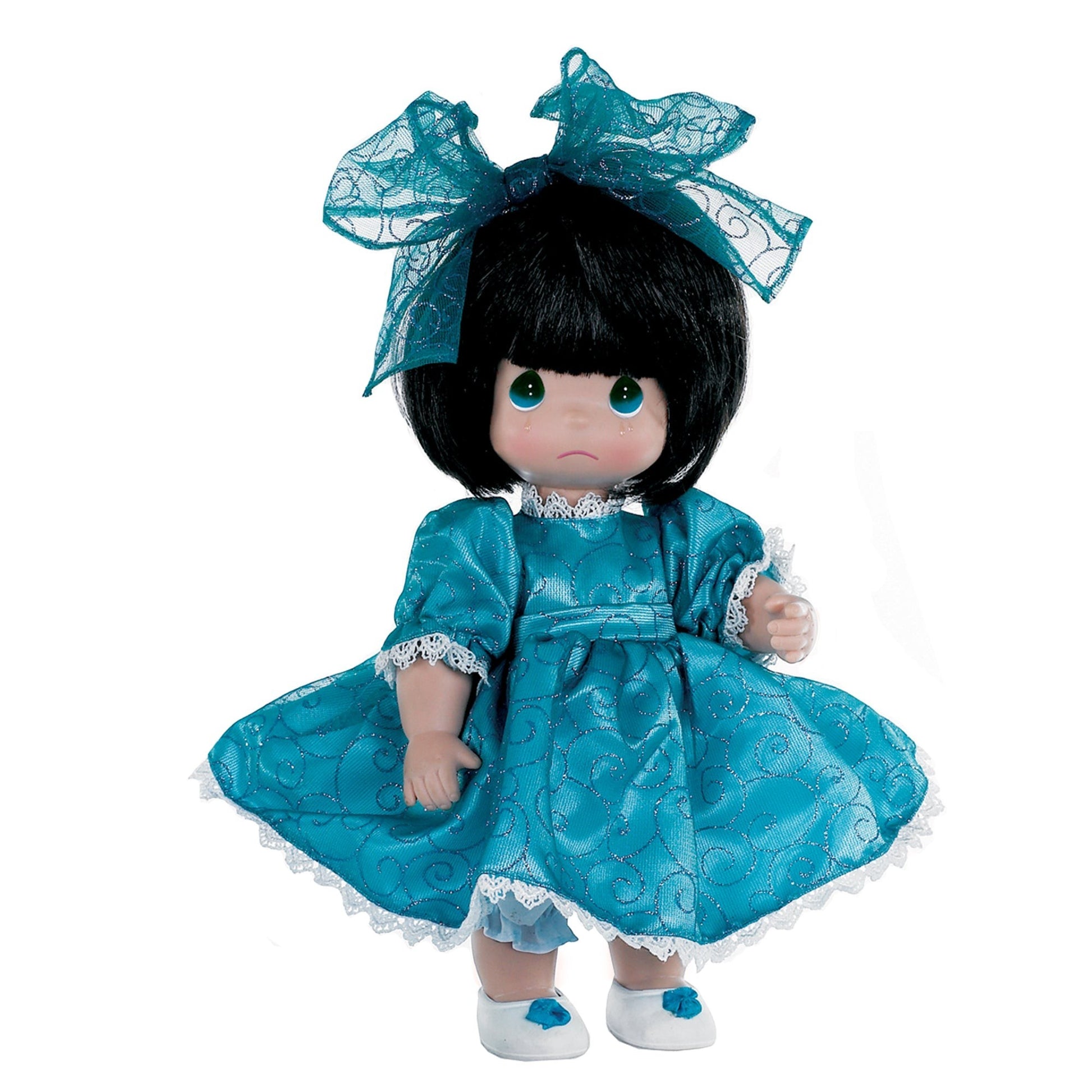 The Doll Maker I'm So Sorry brunette vinyl doll wearing a teal dress with glittery swirls and a matching hair bow.