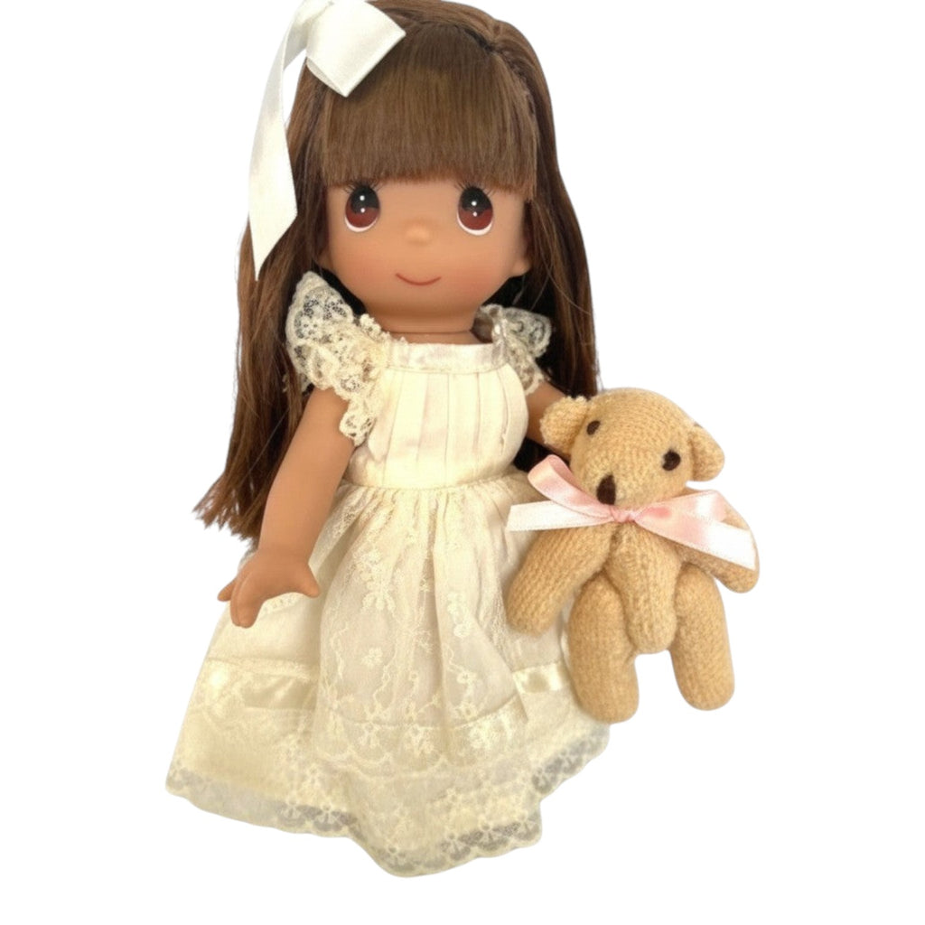 The Doll Maker Cherish Me Always 7-inch brunette vinyl doll wearing an ivory lace gown and holding a small teddy bear.