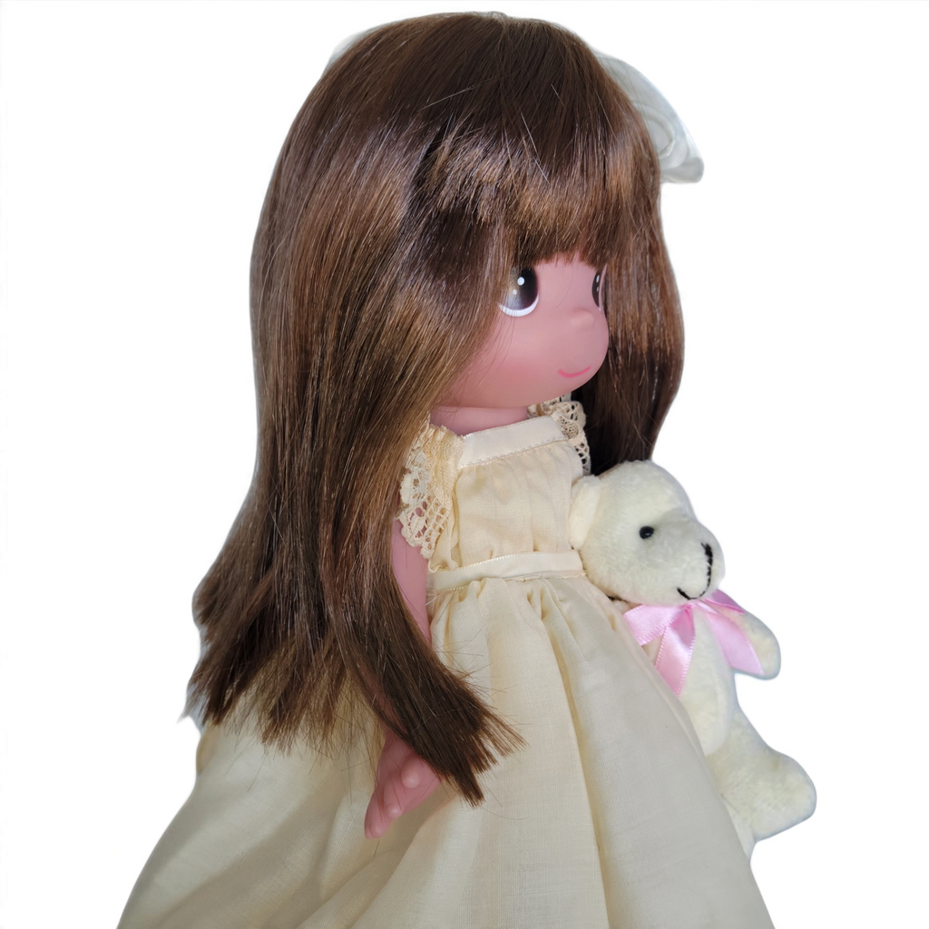 The Doll Maker Cherish Me Always 12-inch auburn hair vinyl doll wearing an ivory lace gown and holding a small bear.