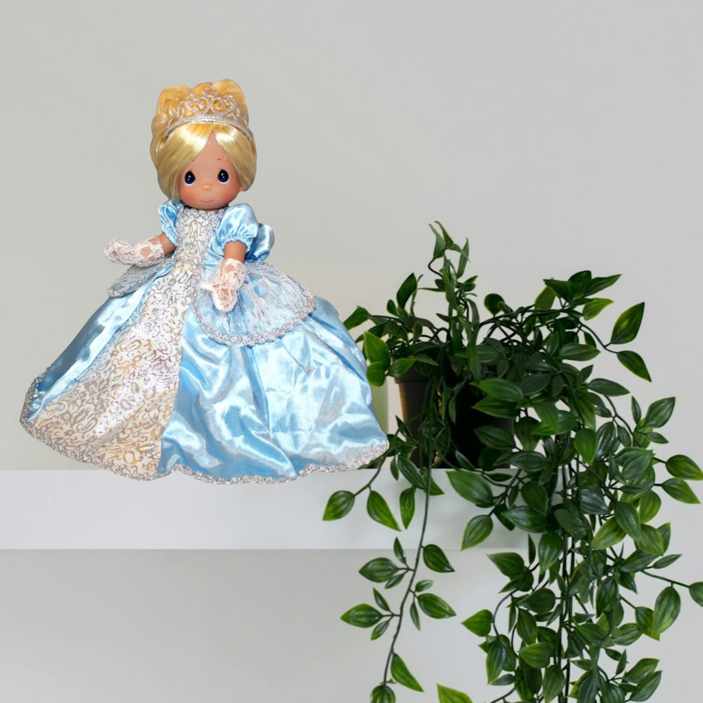 The Doll Maker Cinderella Elegance 12-inch doll wearing a blue satin gown with lace details and a silver tiara.