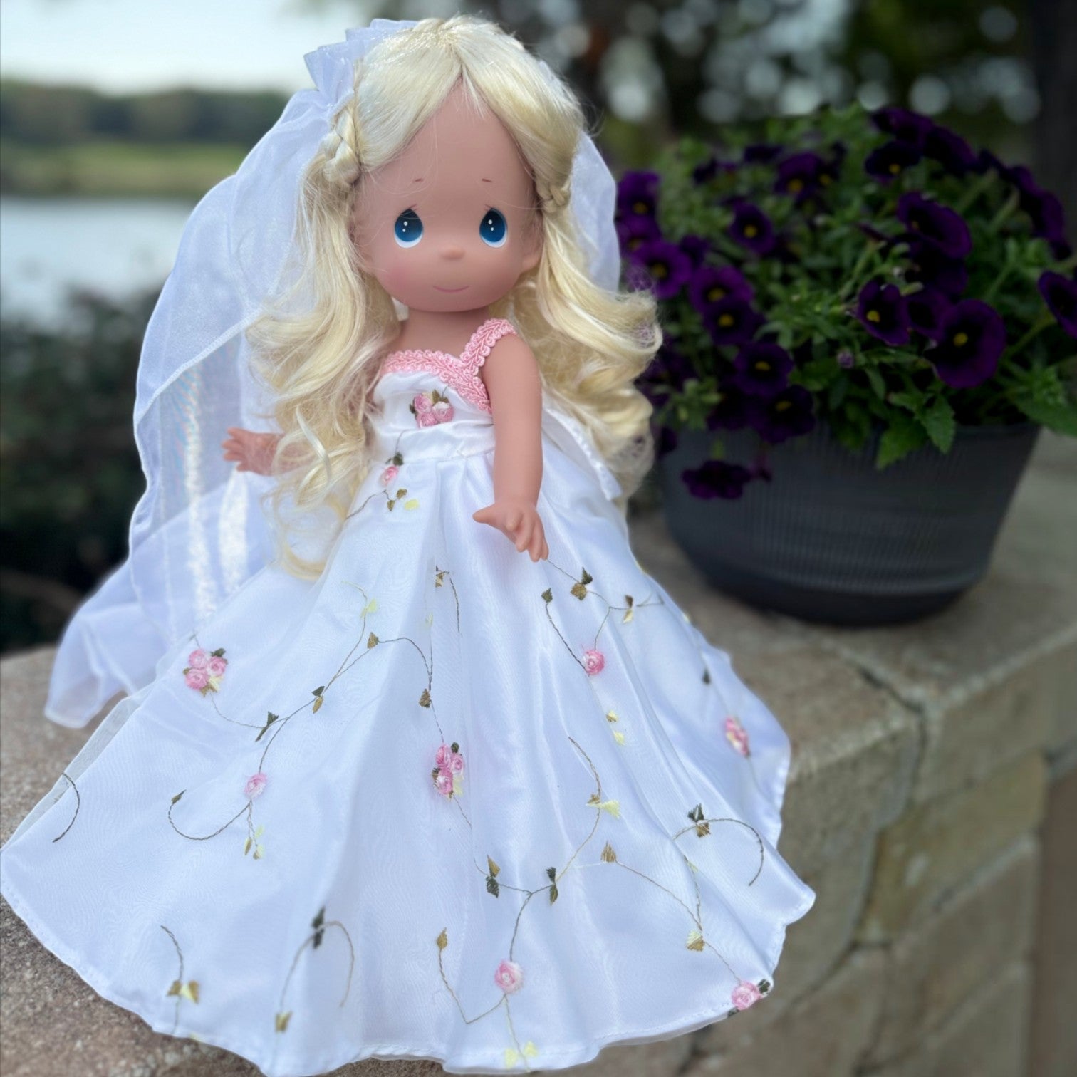 The Doll Maker 12-inch Cinderella wedding doll wearing a white gown with delicate pink floral embroidery and a veil.