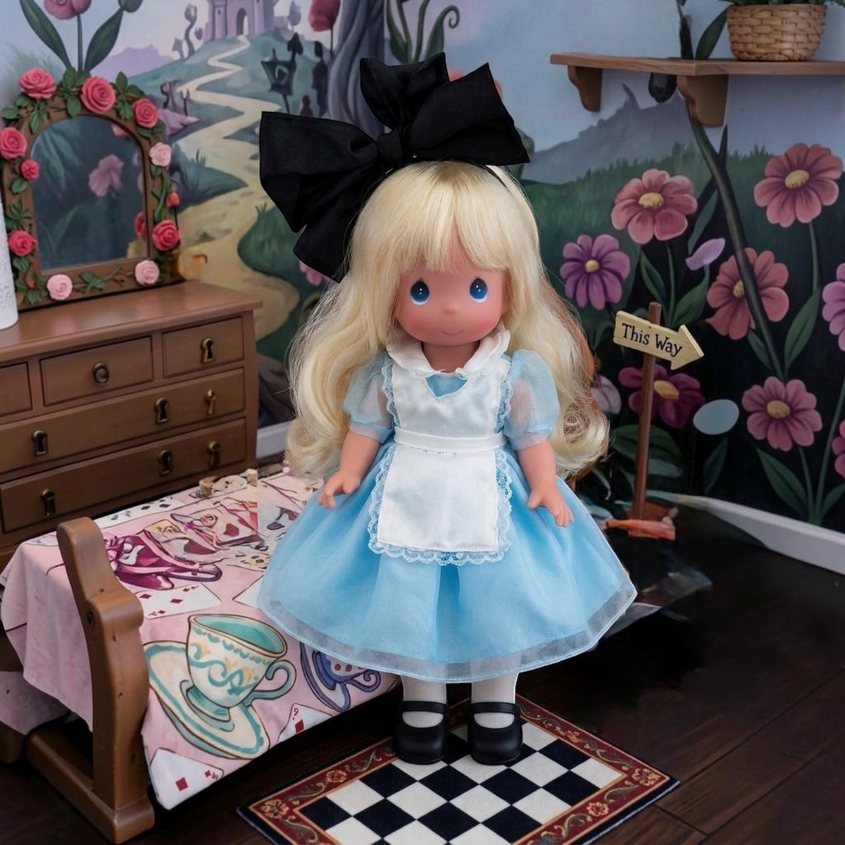 The Doll Maker 12-inch Classic Alice doll wearing a blue dress with white apron and a large black hair bow.