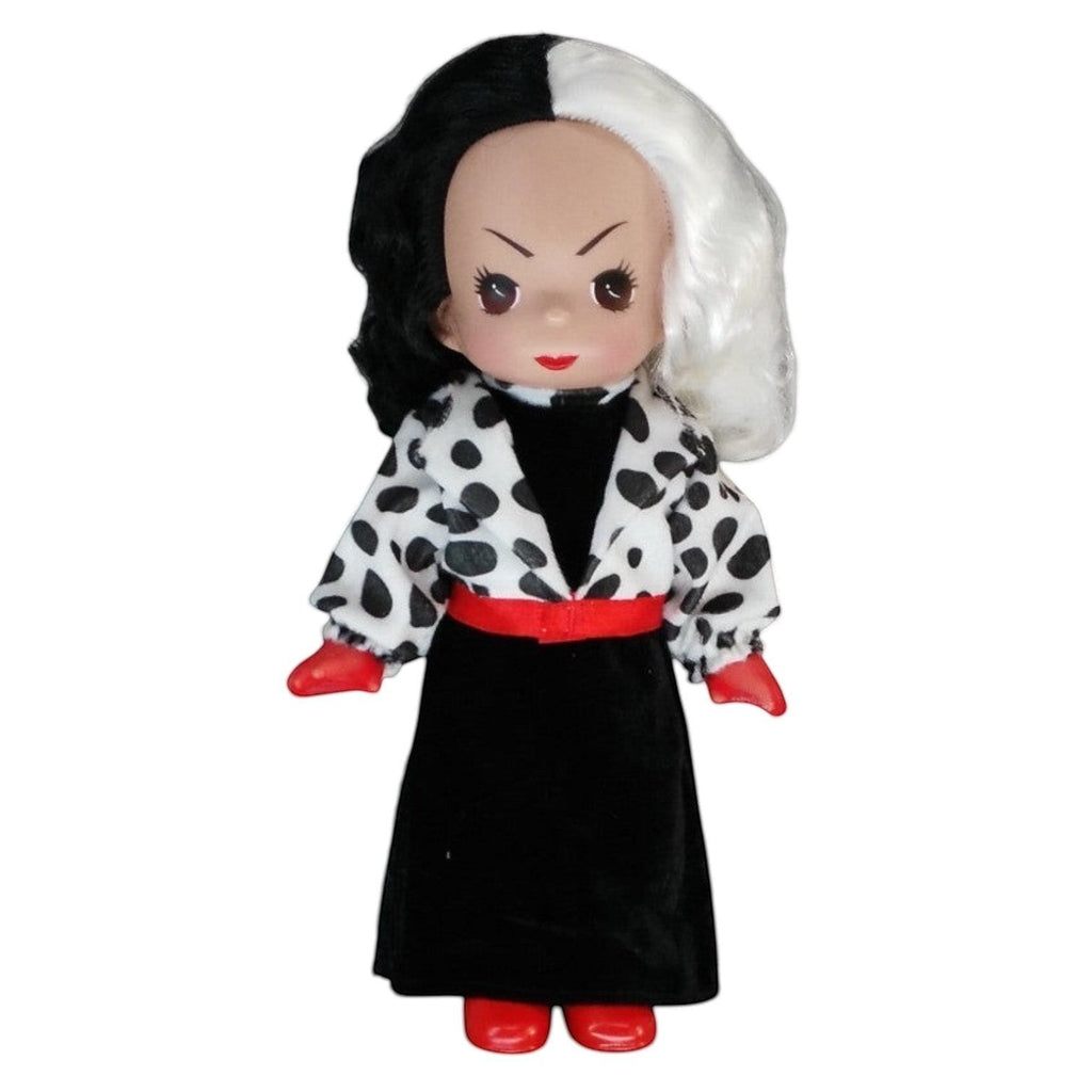 The Doll Maker 12-inch Cruella doll featuring iconic black and white hair, dalmatian print coat, and red accessories.