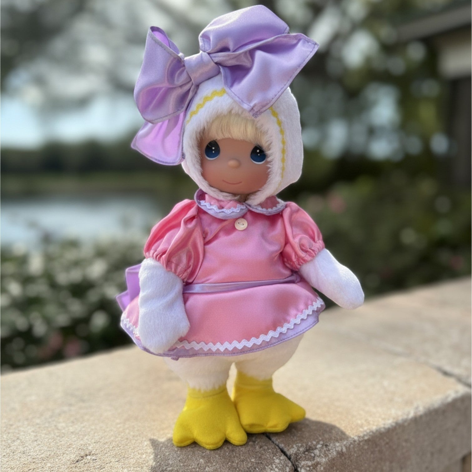 The Doll Maker 12-inch Daisy Duck collectible doll wearing a pink dress and a large purple bow