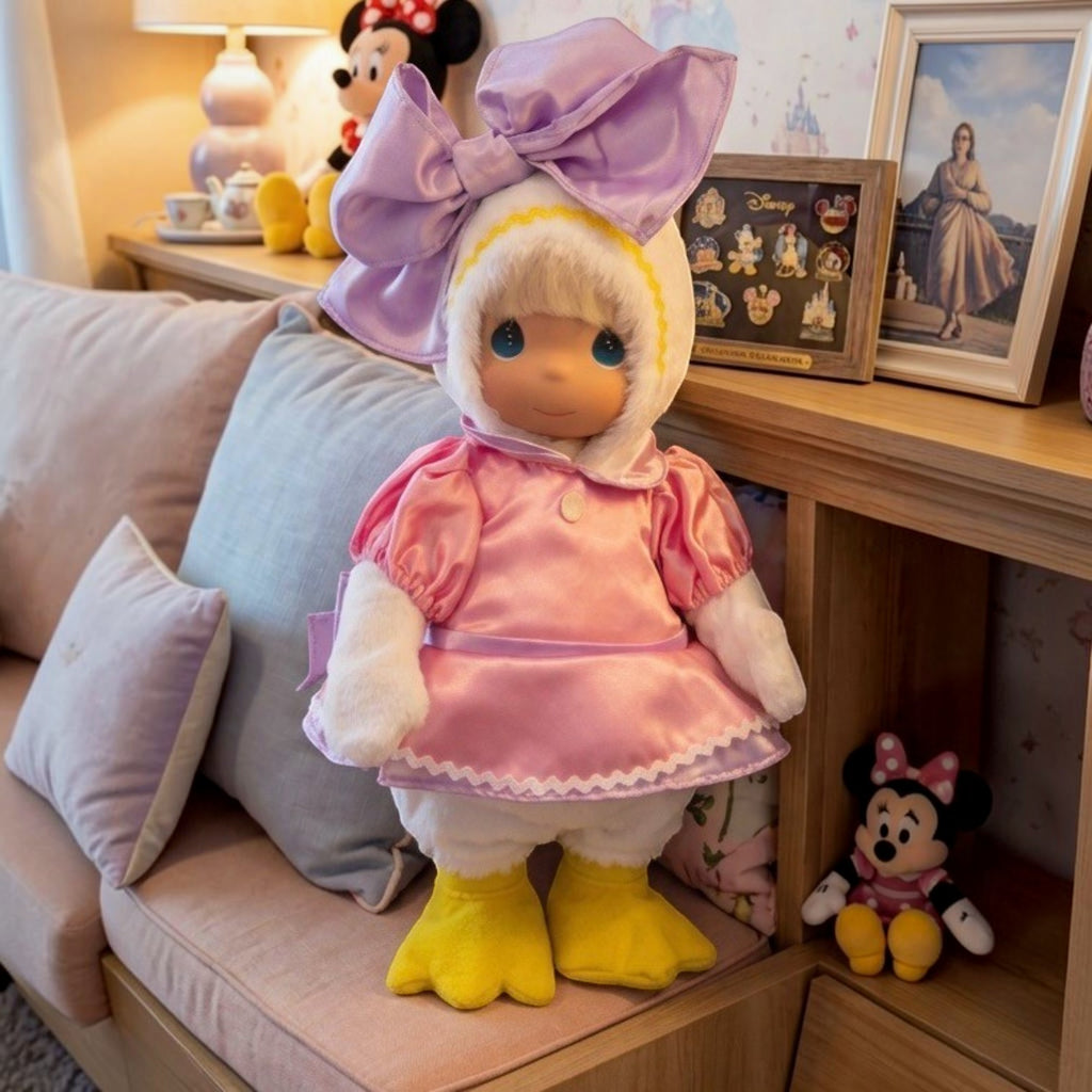 The Doll Maker 12-inch Daisy Duck collectible doll wearing a pink satin dress, white hood, and large purple bow.