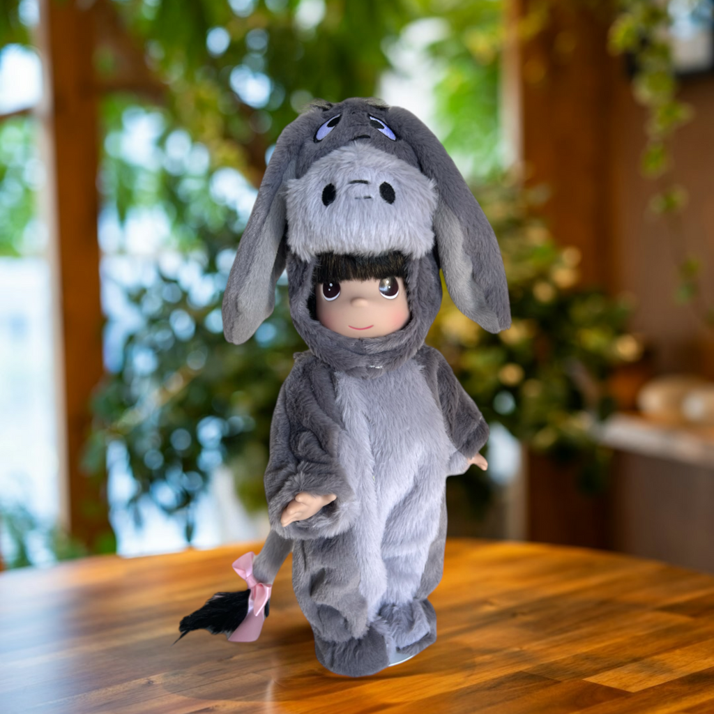 The Doll Maker 12-inch Eeyore collectible doll wearing a soft grey plush donkey onesie with a pink tail ribbon.