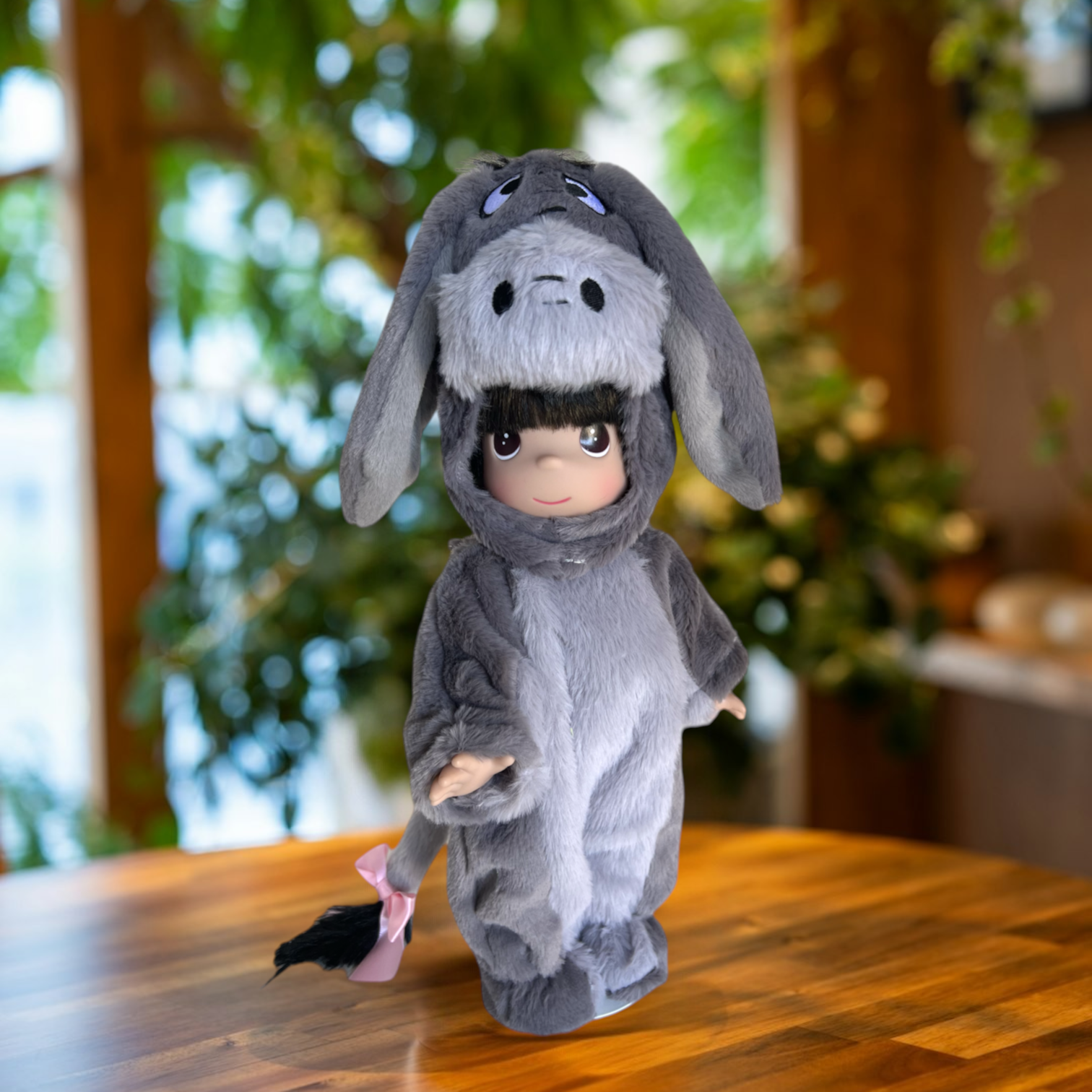 The Doll Maker 12-inch Eeyore collectible doll wearing a soft grey plush donkey onesie with a pink tail ribbon.