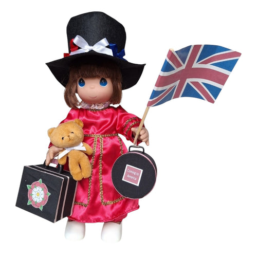 The Doll Maker 16-inch England vinyl doll wearing a red dress and top hat, holding a Union Jack flag and suitcase.