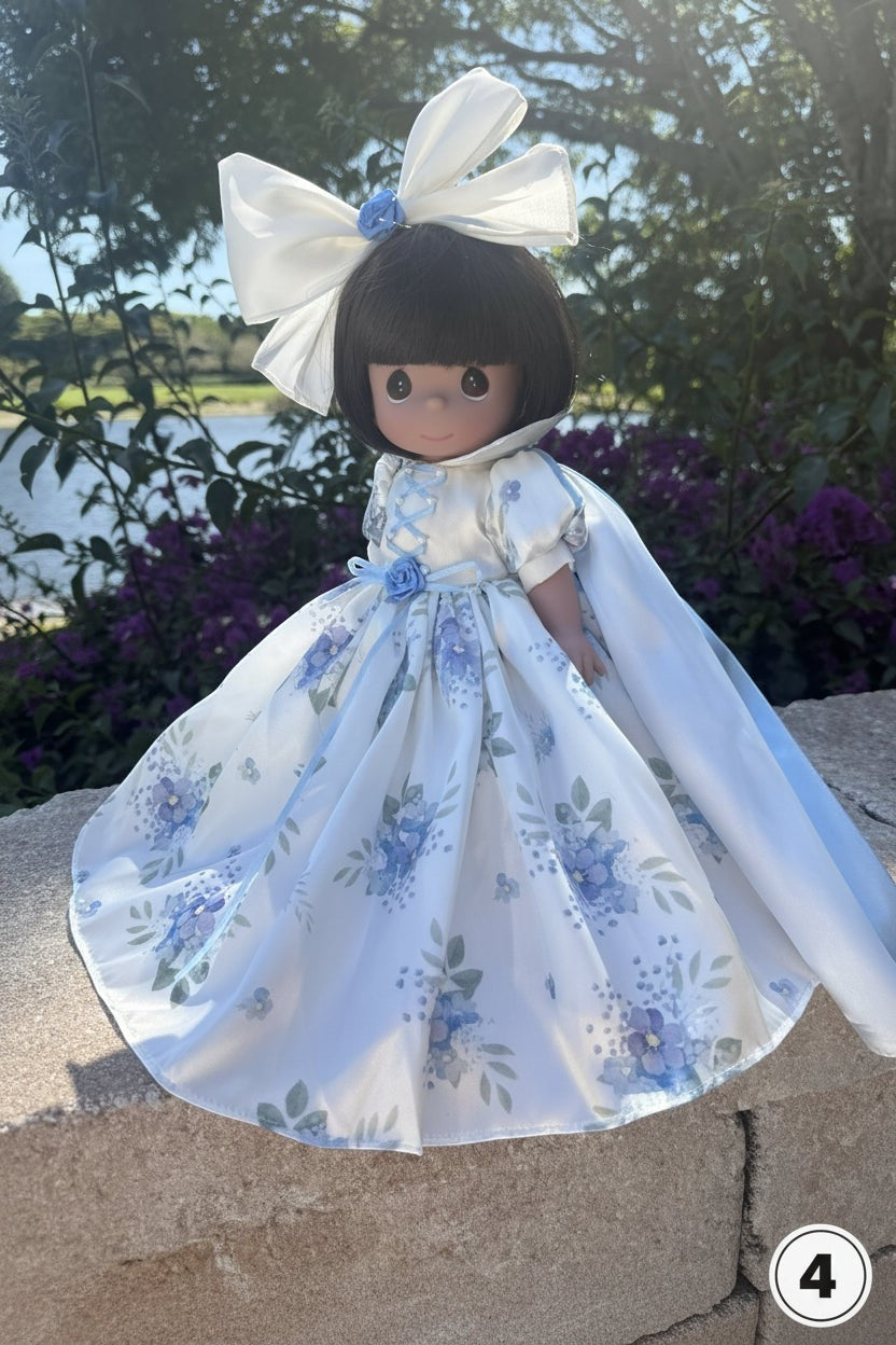 The Doll Maker 12-inch Mother's Day princess doll wearing a white floral gown with a large matching hair bow