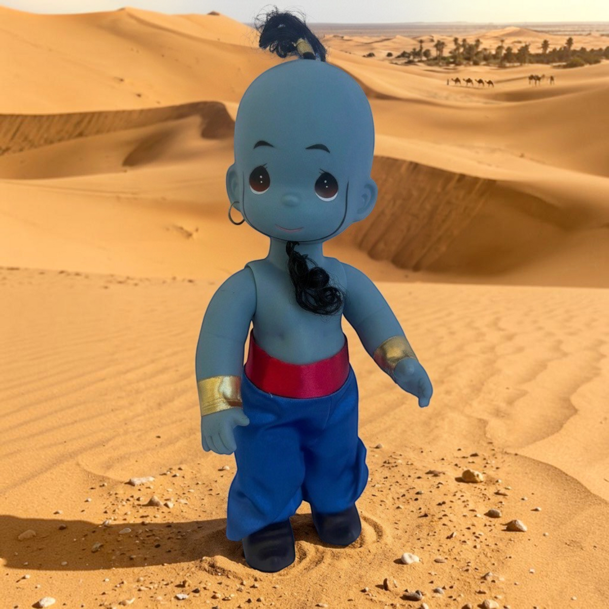 The Doll Maker 12-inch Genie doll from Aladdin featuring blue skin, gold cuffs, and red sash in a desert setting.