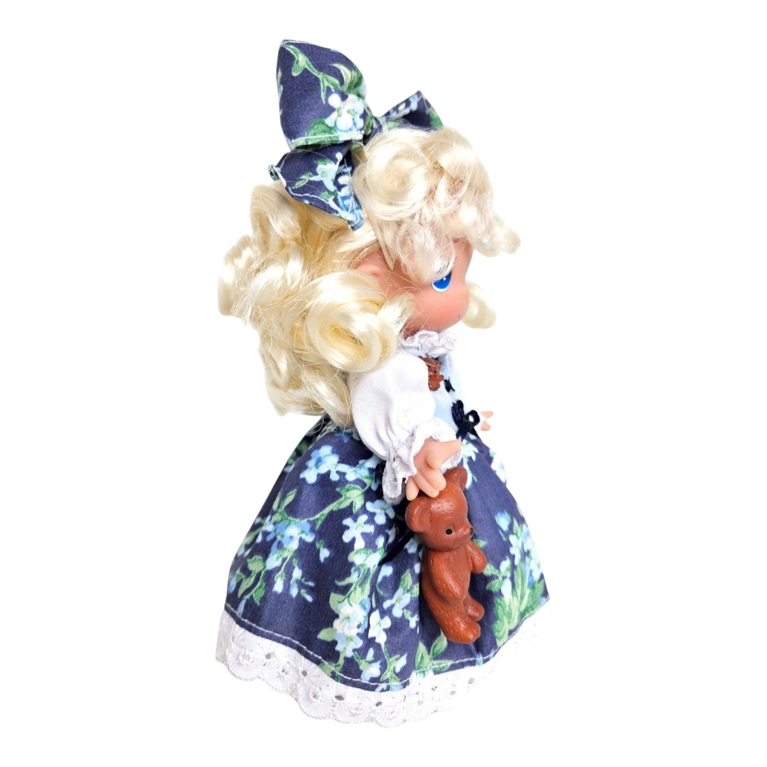The Doll Maker 7-inch Goldilocks vinyl doll with blonde curls, wearing a blue floral dress and holding a teddy bear.